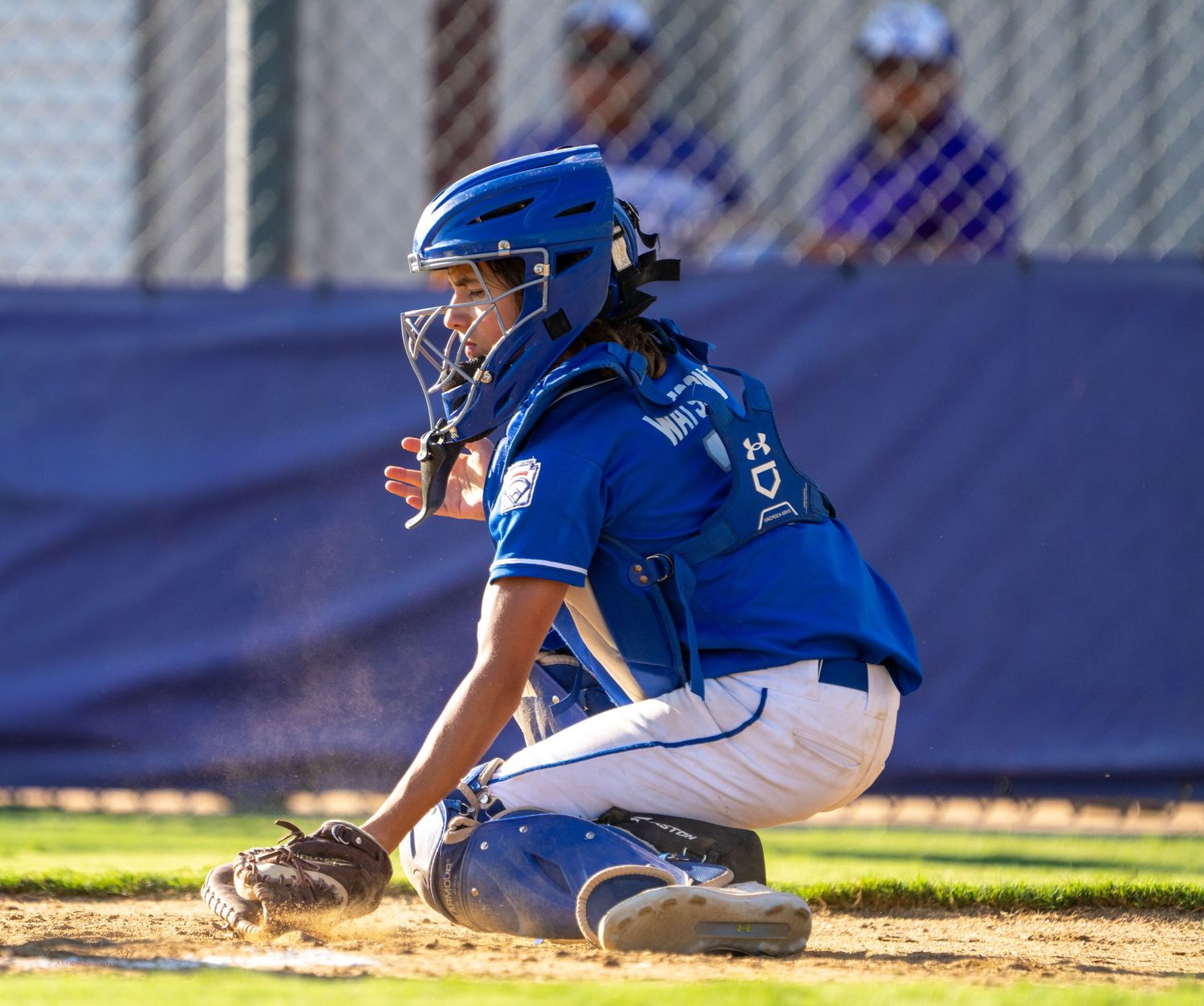 A baseball player in blue uniform slides into home plate during a close play at the plate.