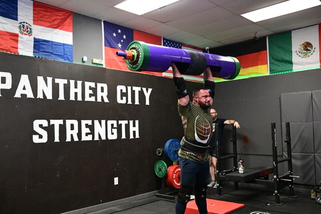 Inside a CrossFit gym with various flags hanging from the ceiling and workout equipment along the walls.