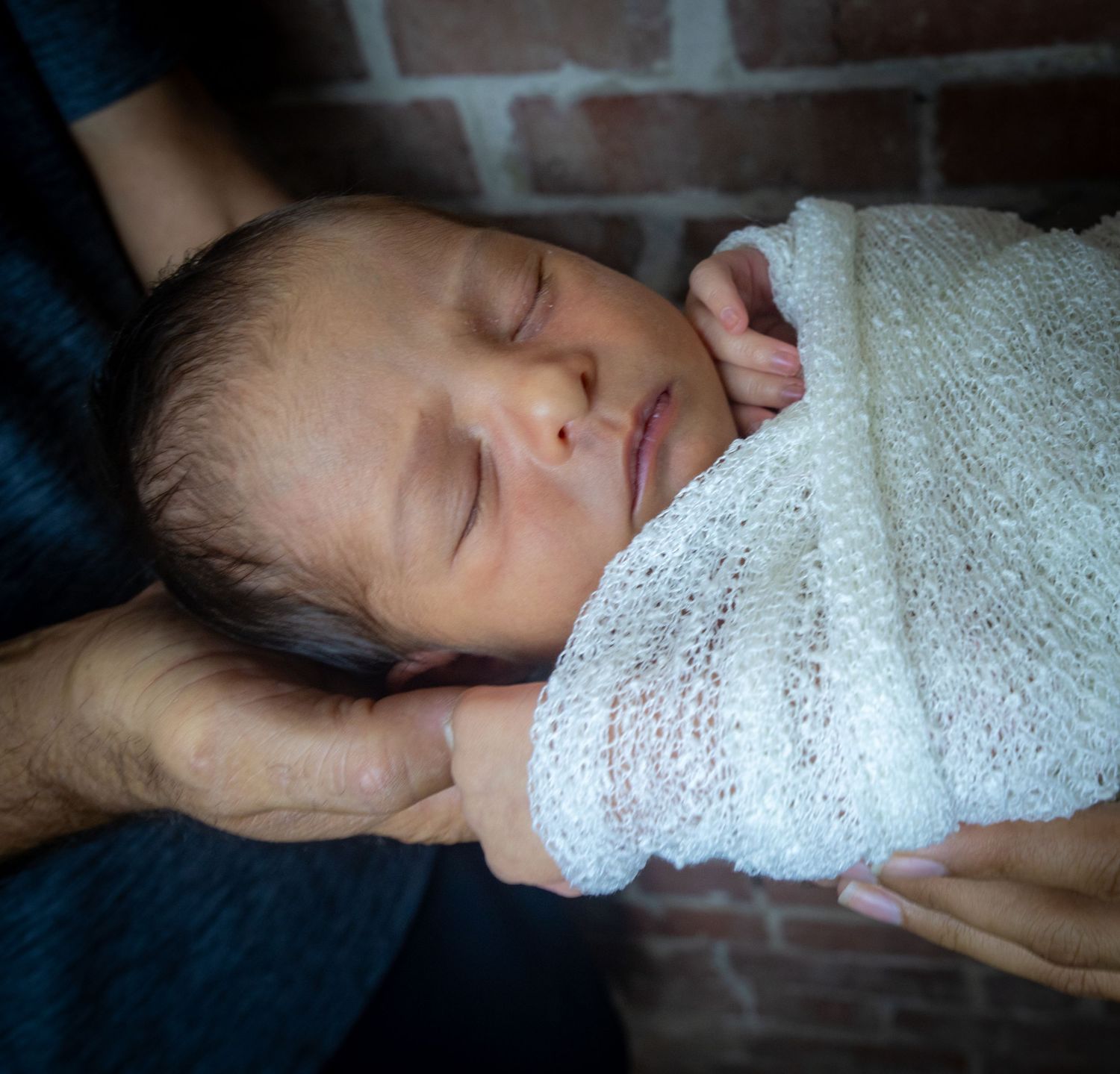 Peaceful sleeping newborn baby wrapped in soft white blanket.