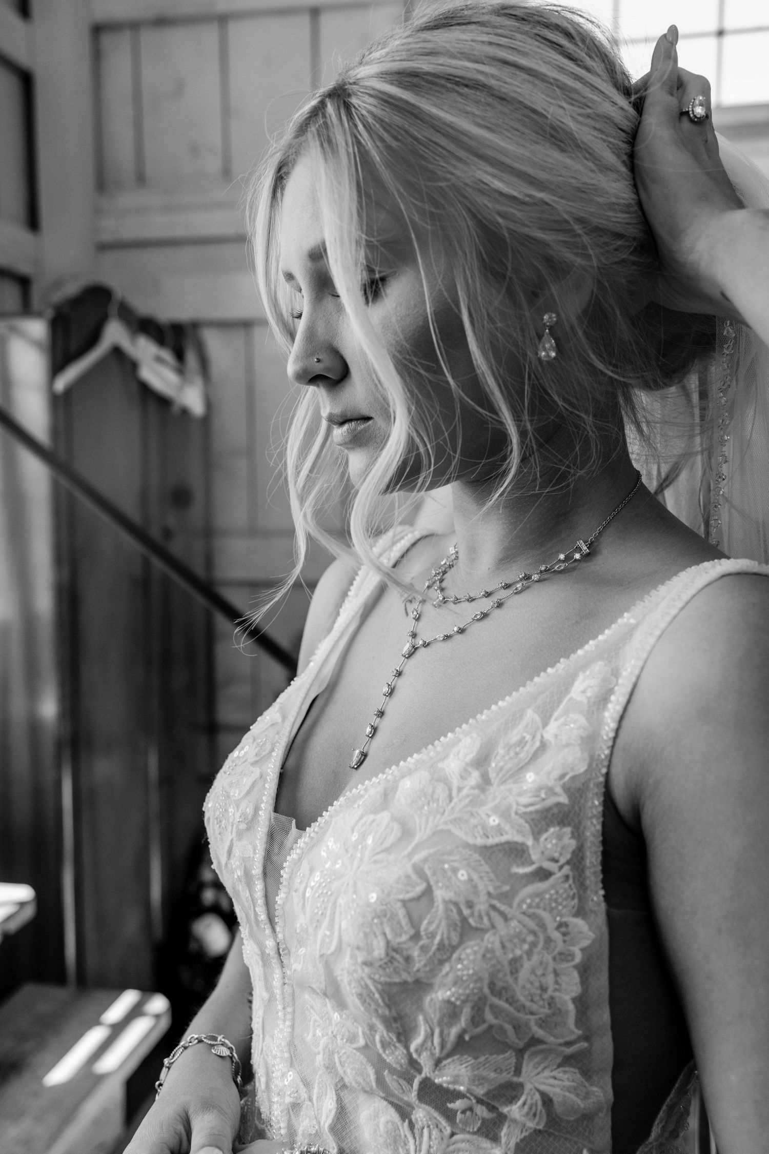 A series of black and white photos showing close-up details of a bride wearing a lace wedding dress and pearl necklace.