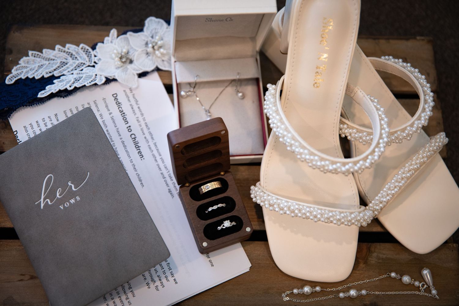 Wedding accessories including vows book, jewelry box, and beaded sandals.