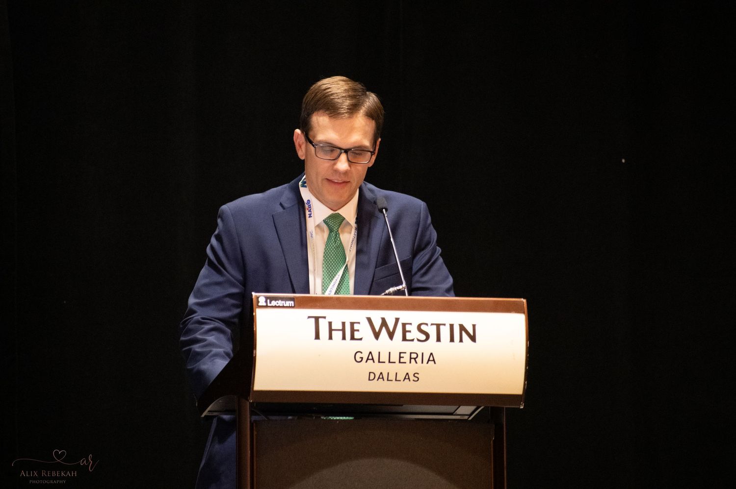 Speaker presenting at podium during conference at The Westin Galleria Dallas.
