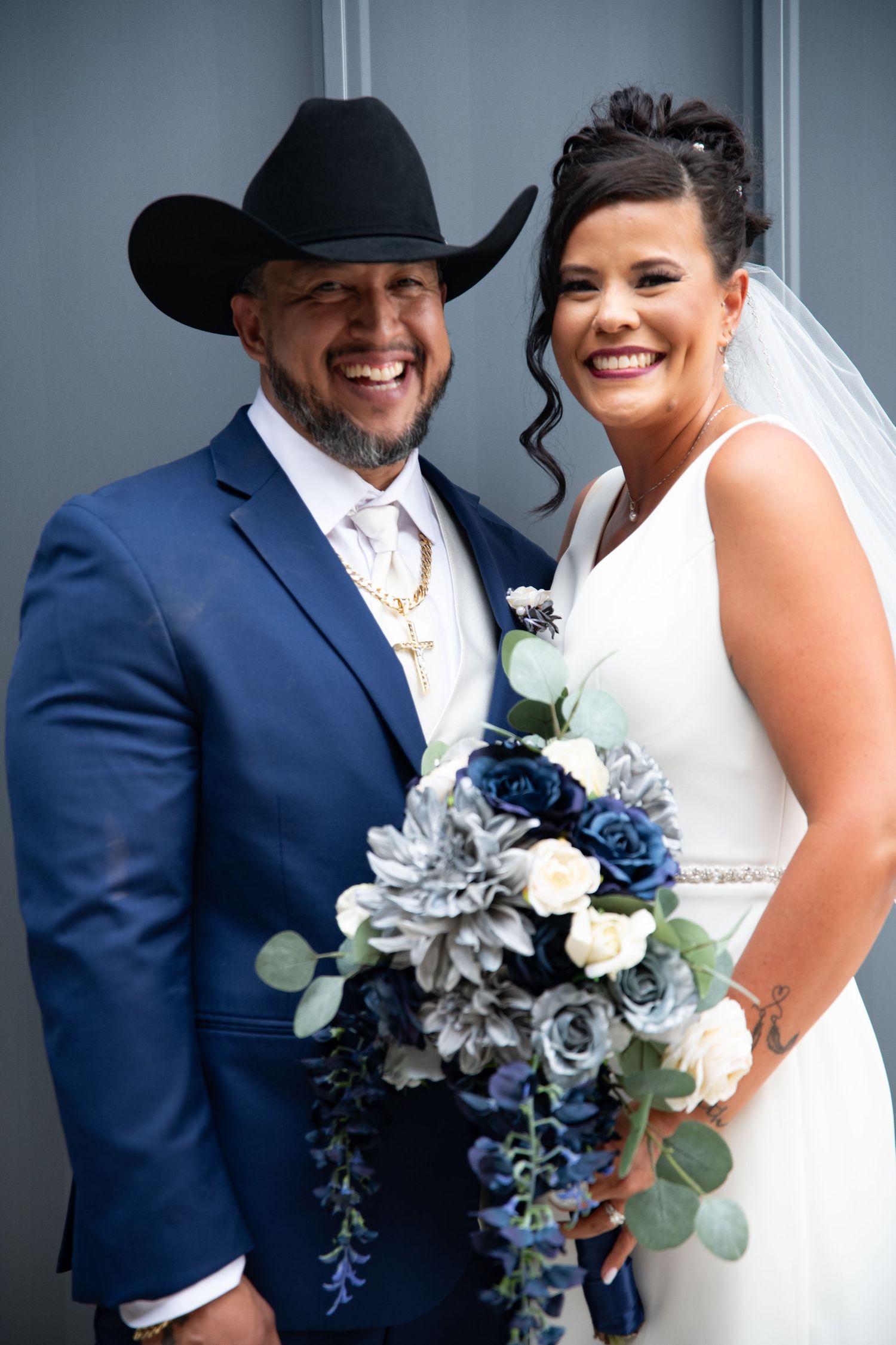 A western-themed wedding couple with a navy and silver bouquet featuring roses and eucalyptus.