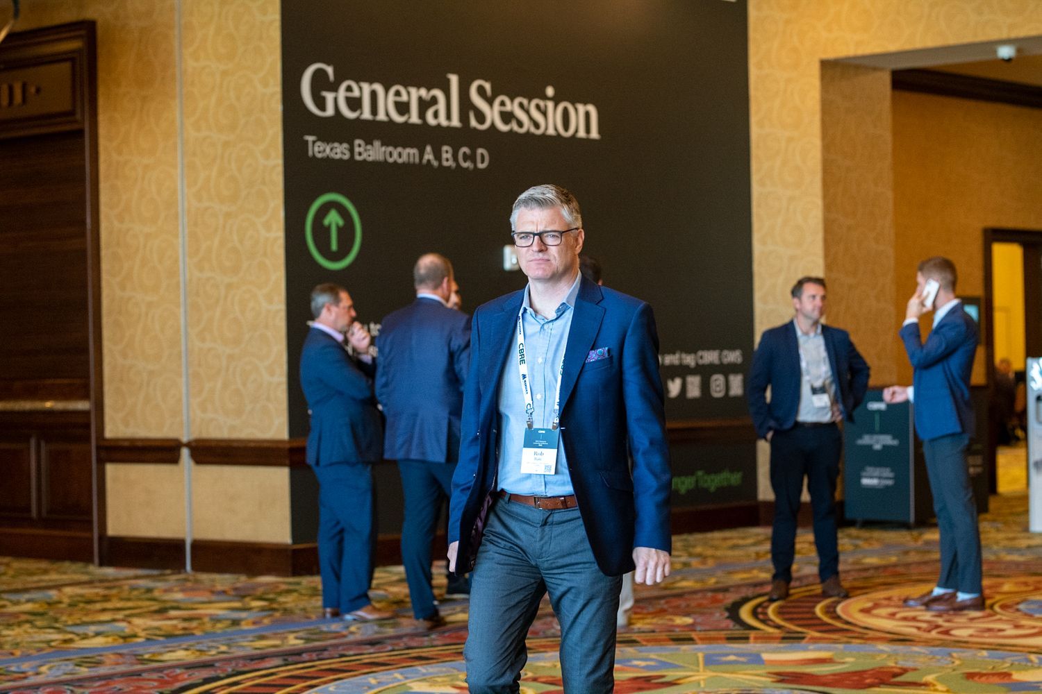 Business professional standing near General Session signage at a conference venue.