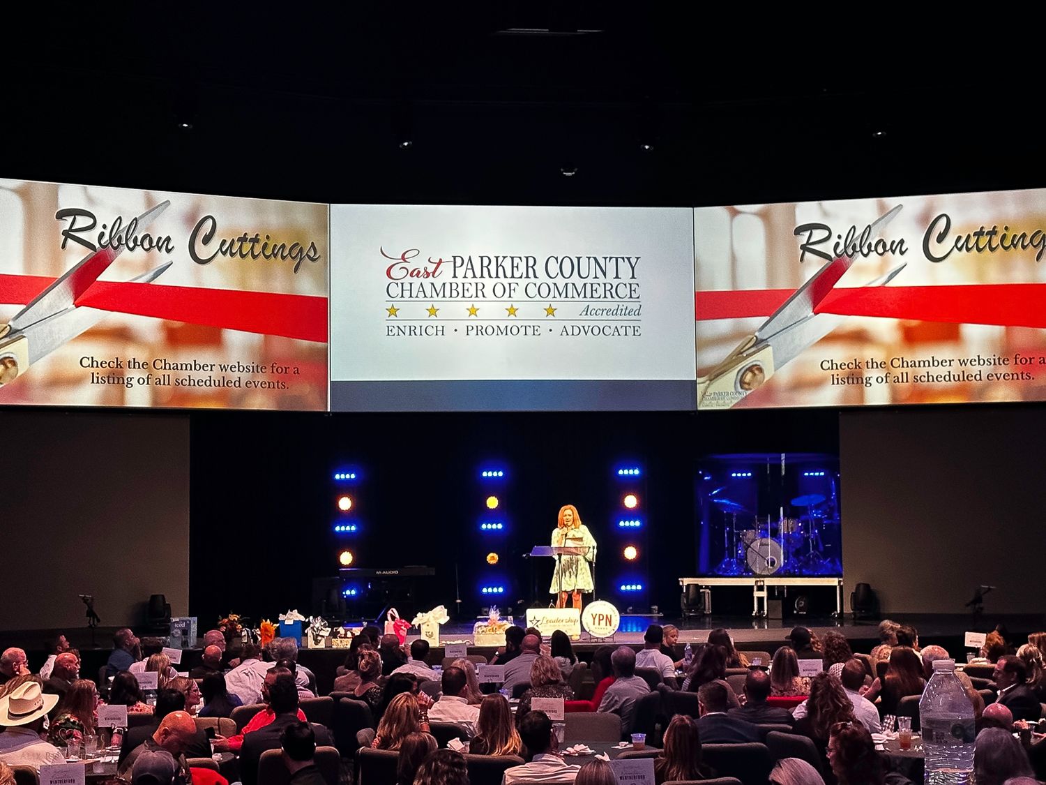 Large audience gathering at Parker County Chamber event with stage and presentation screens.