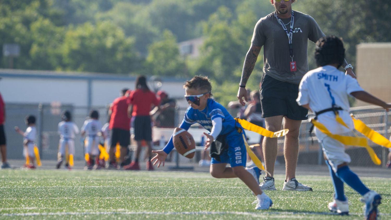 Young flag football players in action on a turf field during a competitive youth sports match.