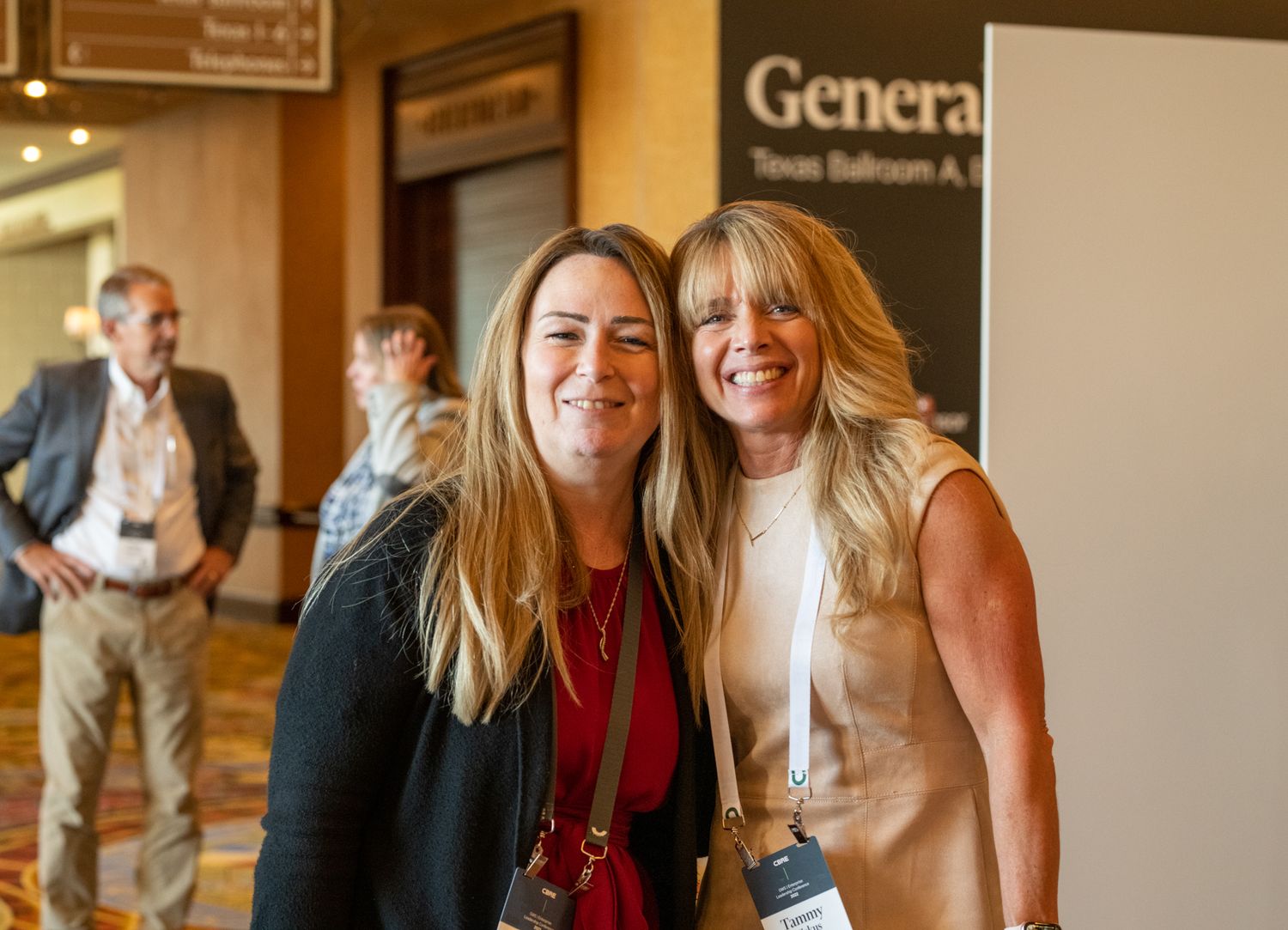Event attendees sharing a friendly moment near conference signage.