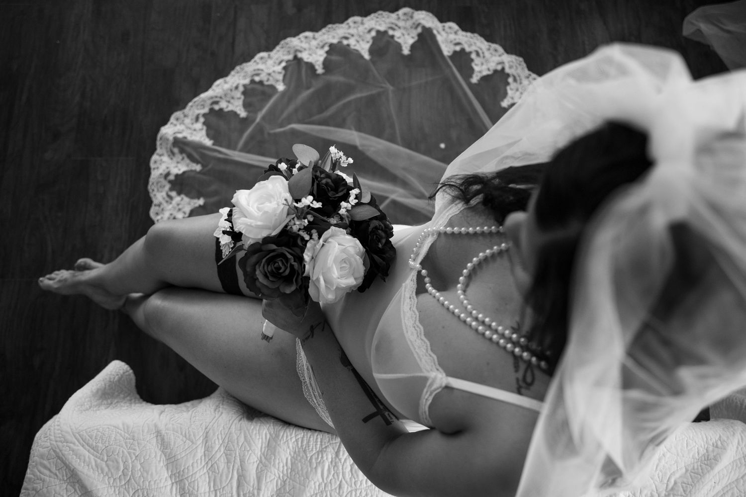 Black and white detail of lace veil and floral corsage arrangement.