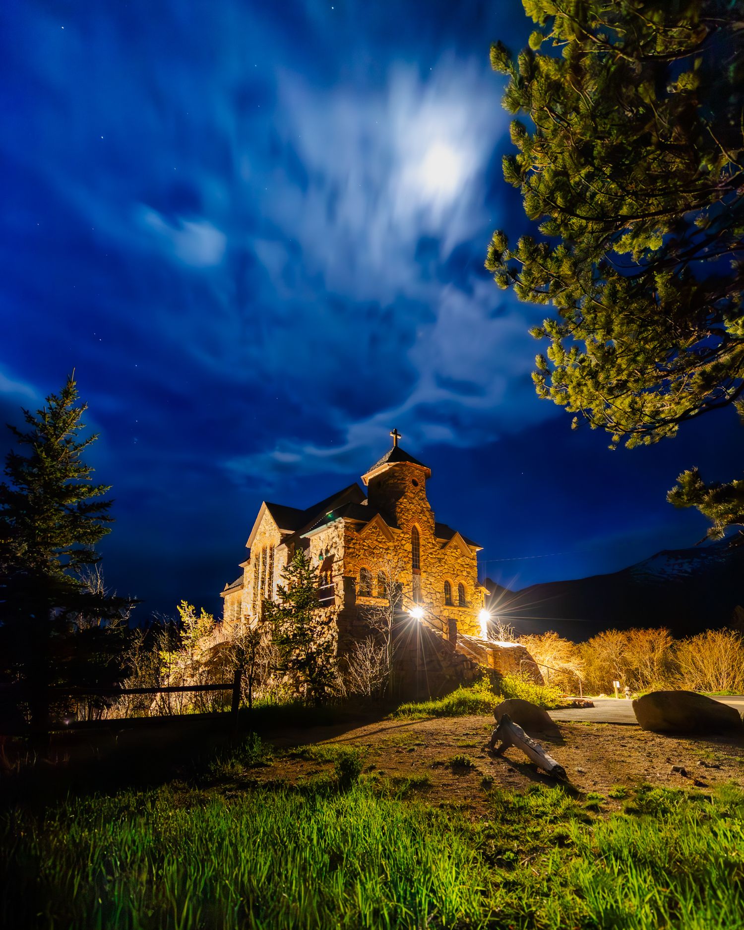 Historic stone church illuminated at night under a dramatic moonlit sky.