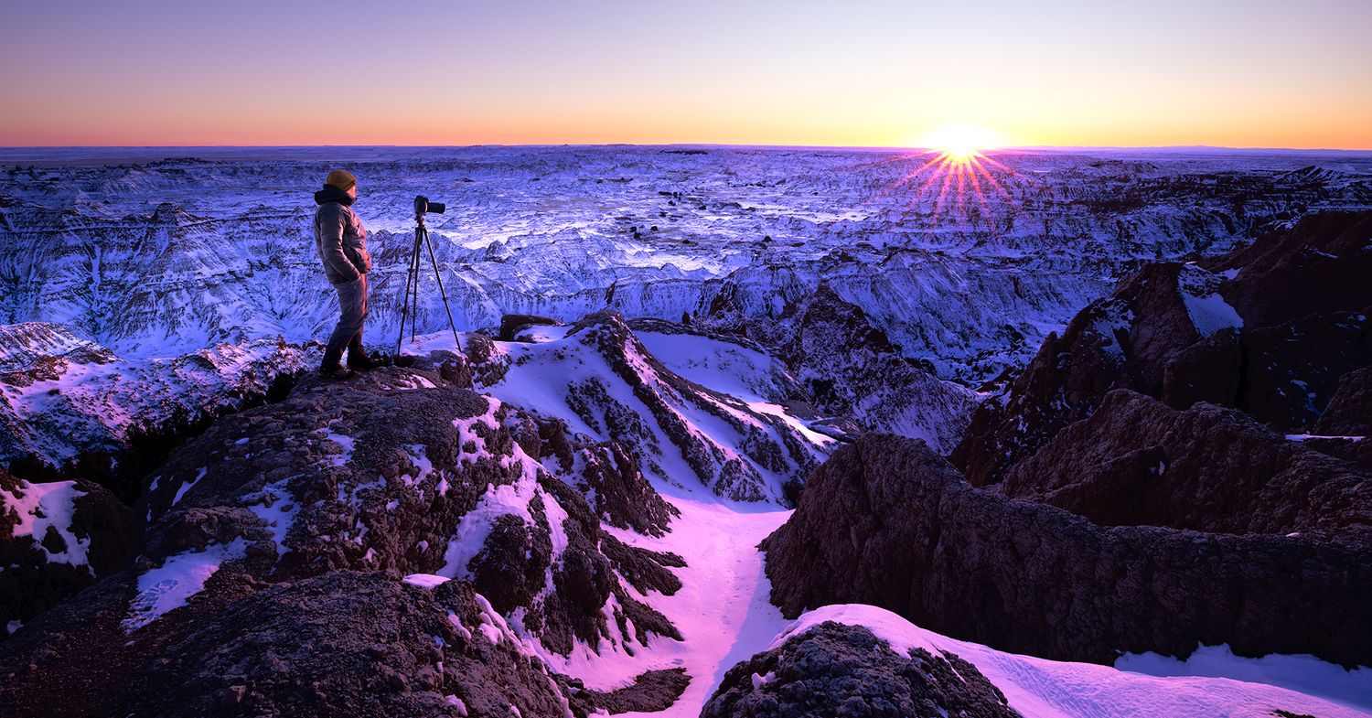 Majestic mountain landscape at sunset with snow-covered peaks reflecting pink and purple hues. Badlands National Park