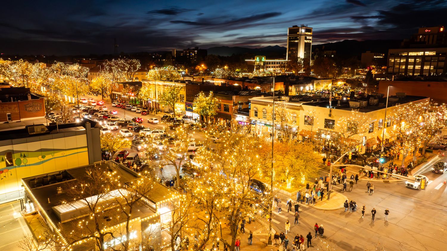 Nighttime cityscape panorama with glowing golden lights illuminating the streets and buildings.