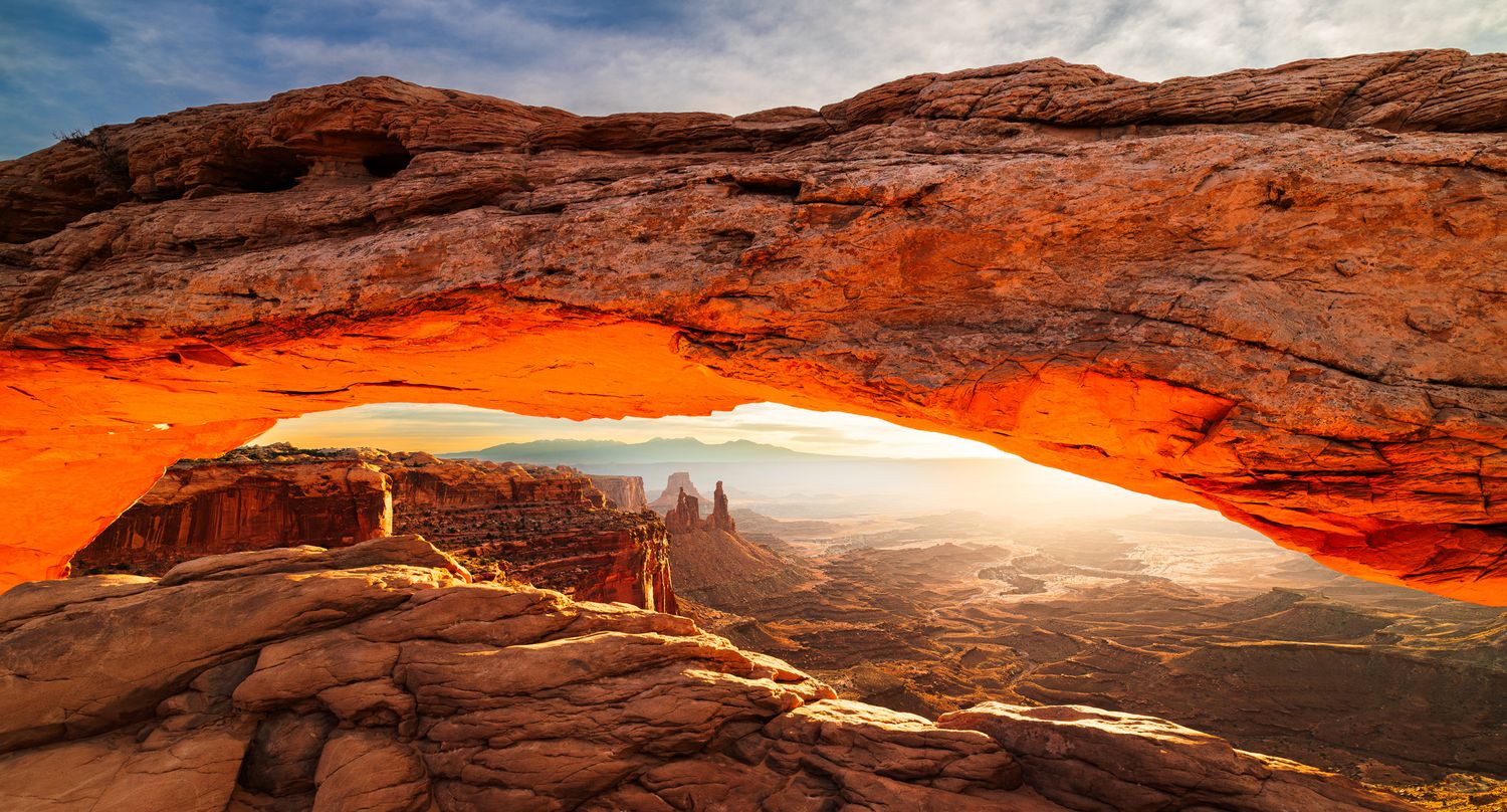 Natural rock arch formation in red sandstone glowing at sunset. Mesa Arch in Canyonlands National Park.