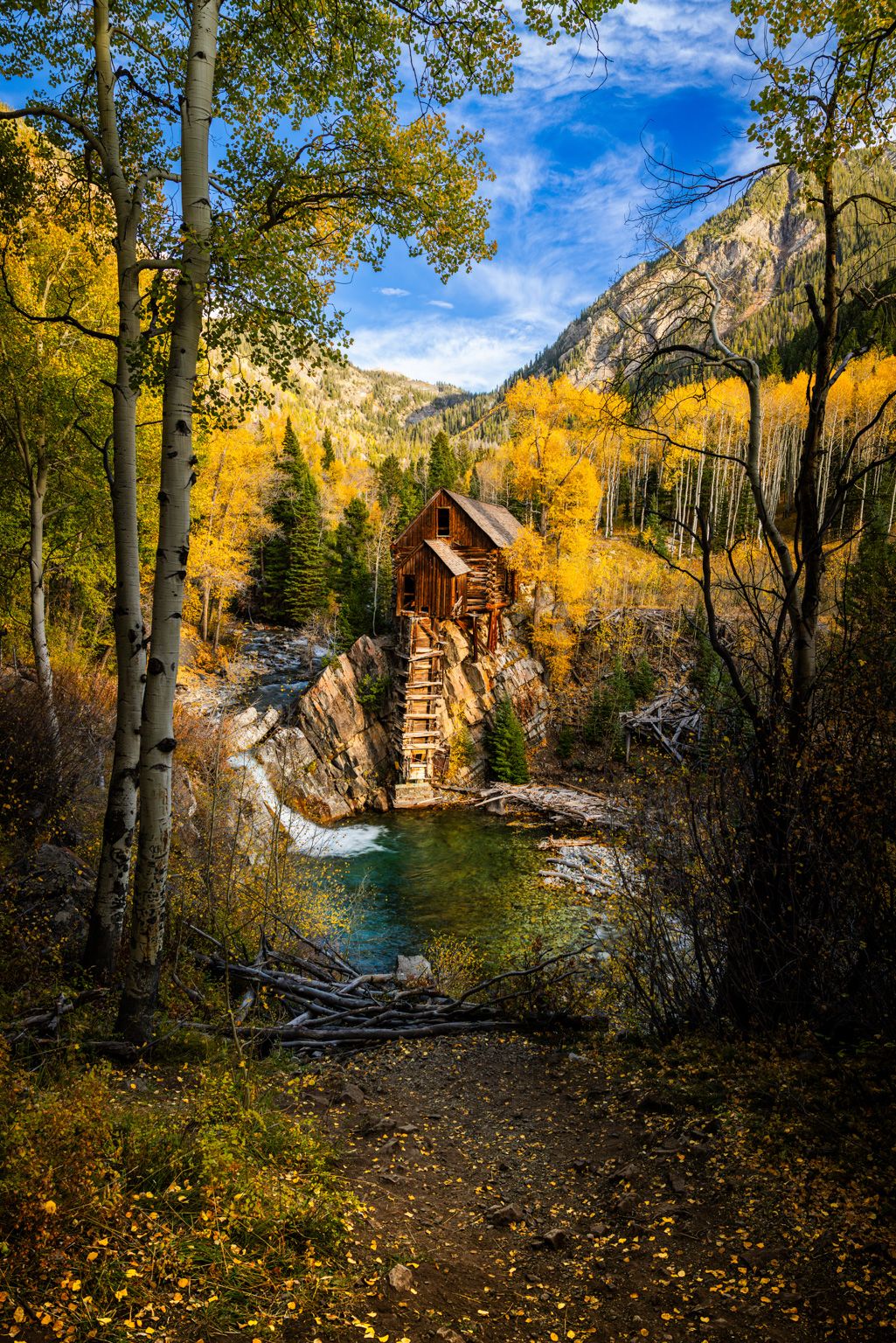 Historic Crystal Mill surrounded by golden aspen trees in Colorado's autumn landscape.