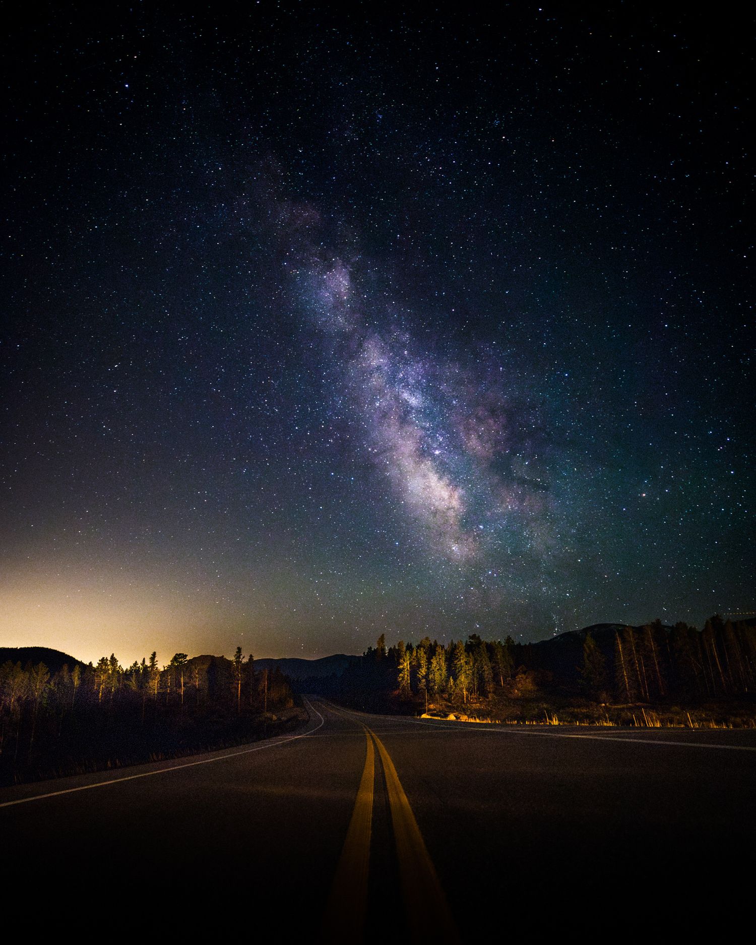 Starry night sky with Milky Way visible over a dark rural road.