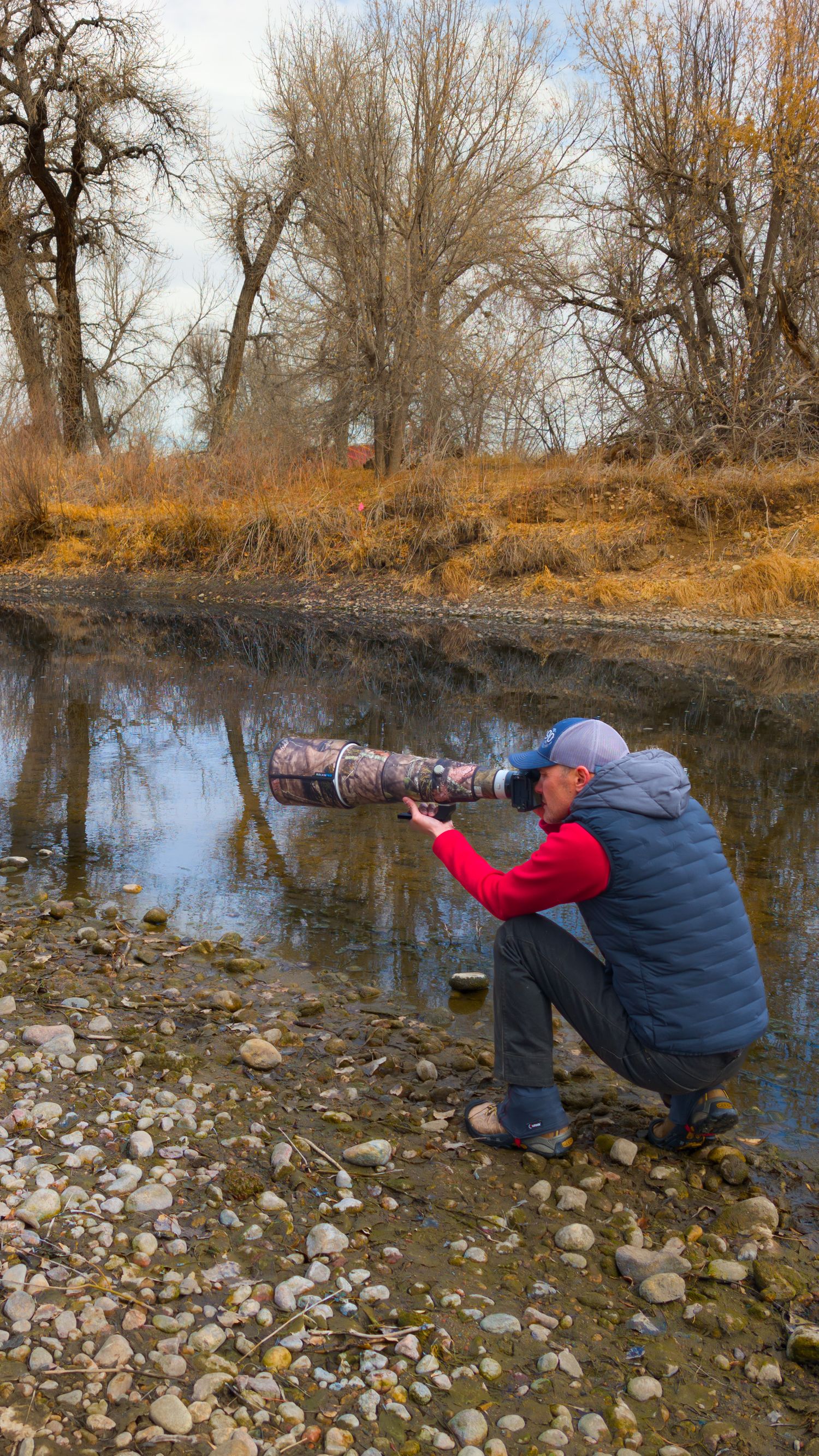 Photographers crouching by rocky riverbank to capture nature shots. Dave Cho
