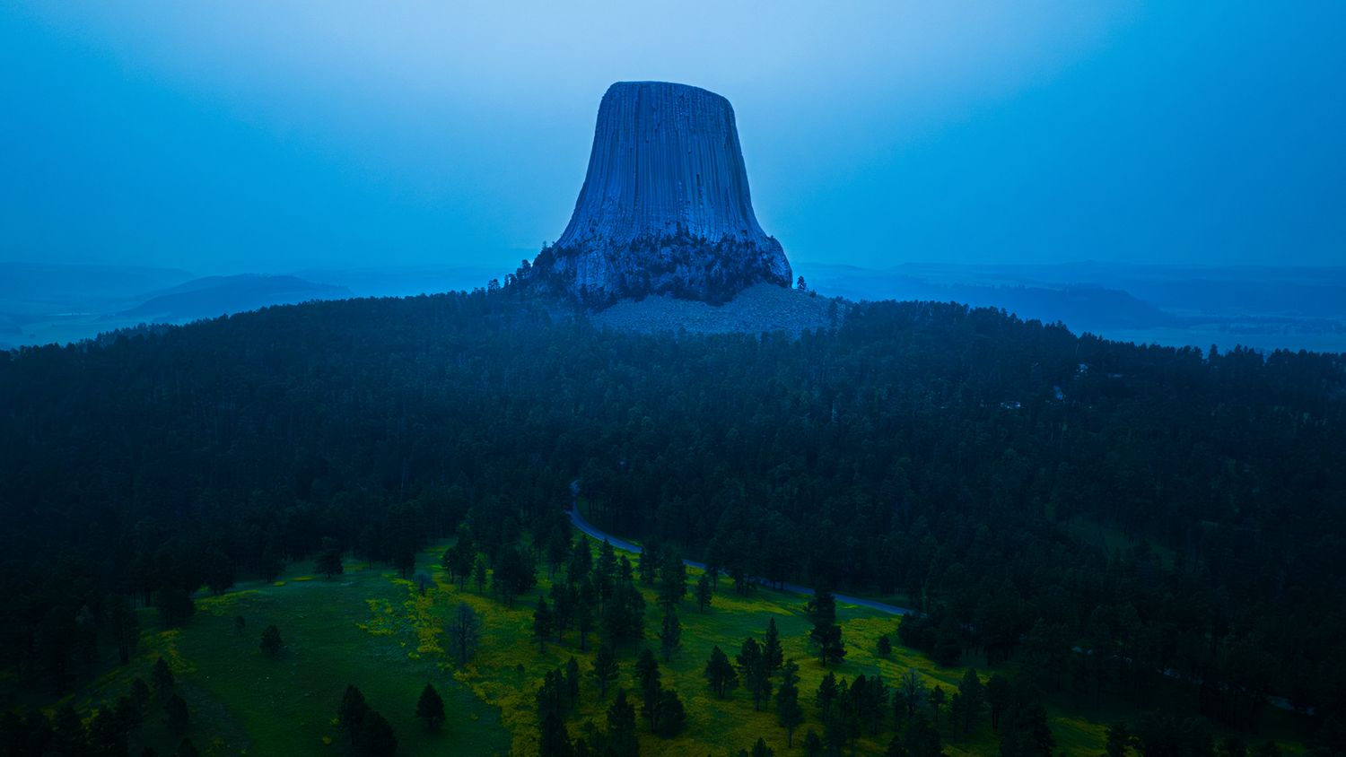Majestic mountain peaks rise against a deep blue sky in a dramatic panoramic landscape. Devils Tower.