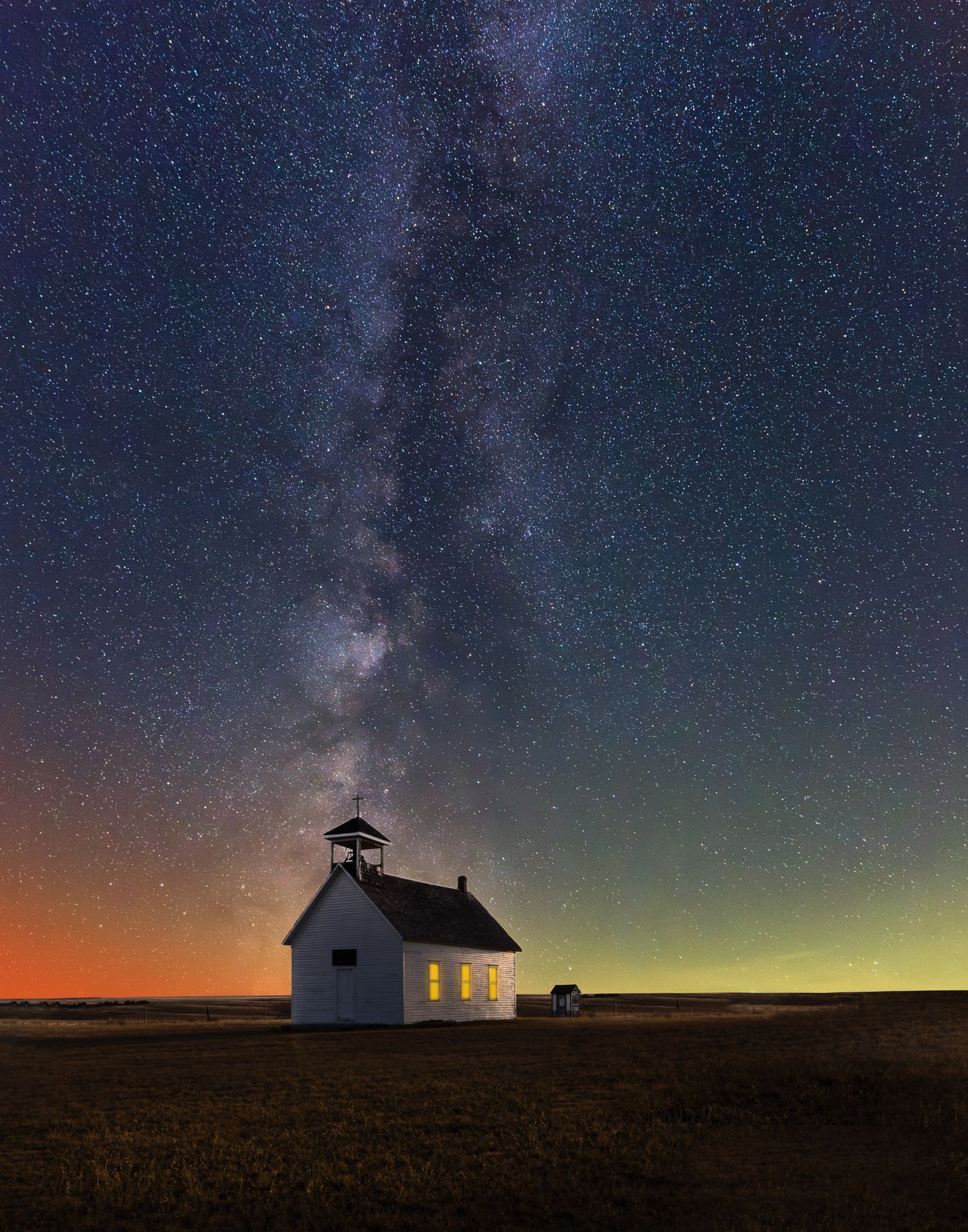 Milky Way galaxy stretching over a small rural church on the prairie.
