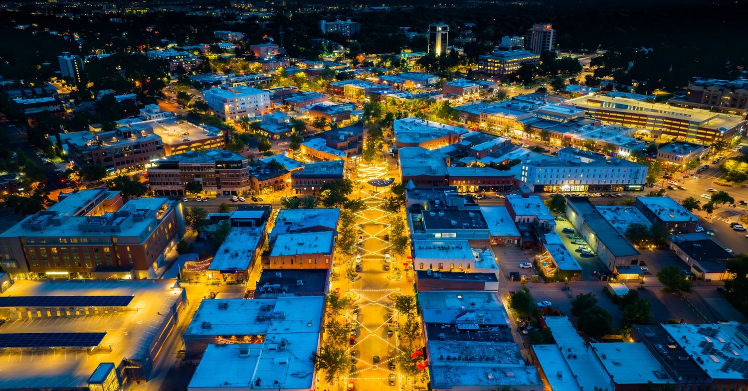 Bird's eye view of city at night with streets glowing in blue and amber lights.