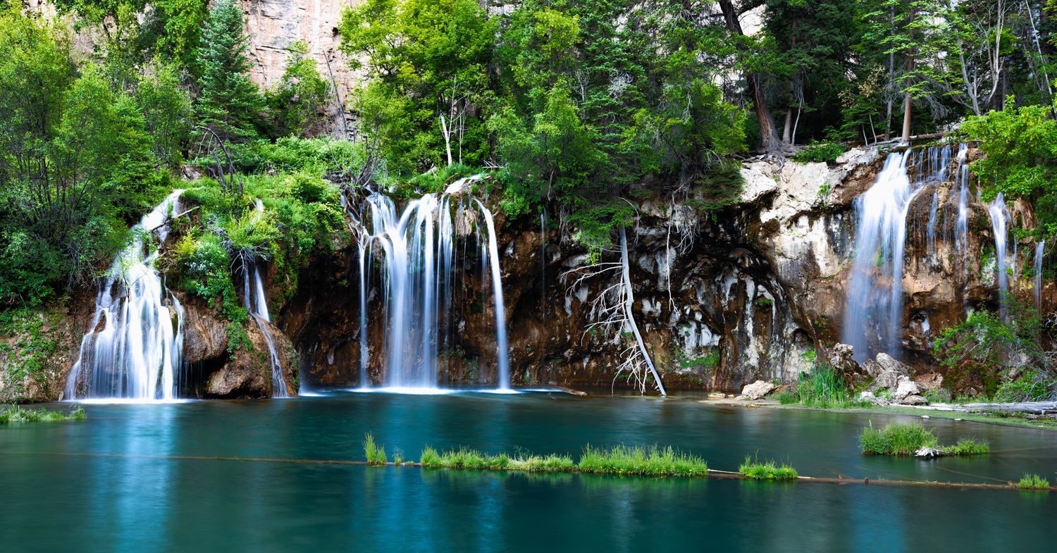 Series of cascading waterfalls flow through lush greenery into turquoise pools. Hidden Lake Colorado