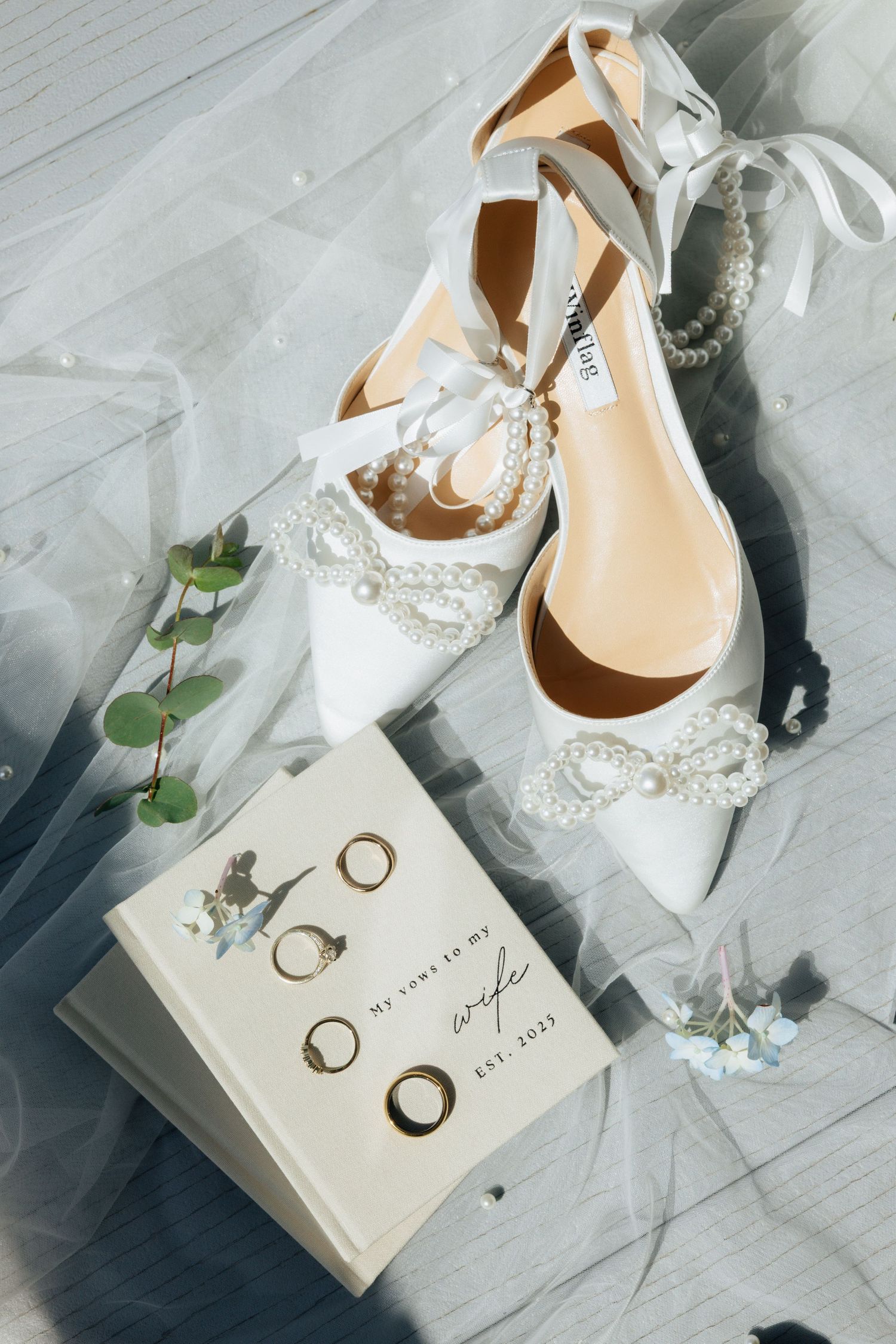 Wedding day details showing a beige wedding invitation and a wedding veil with wedding shoes.