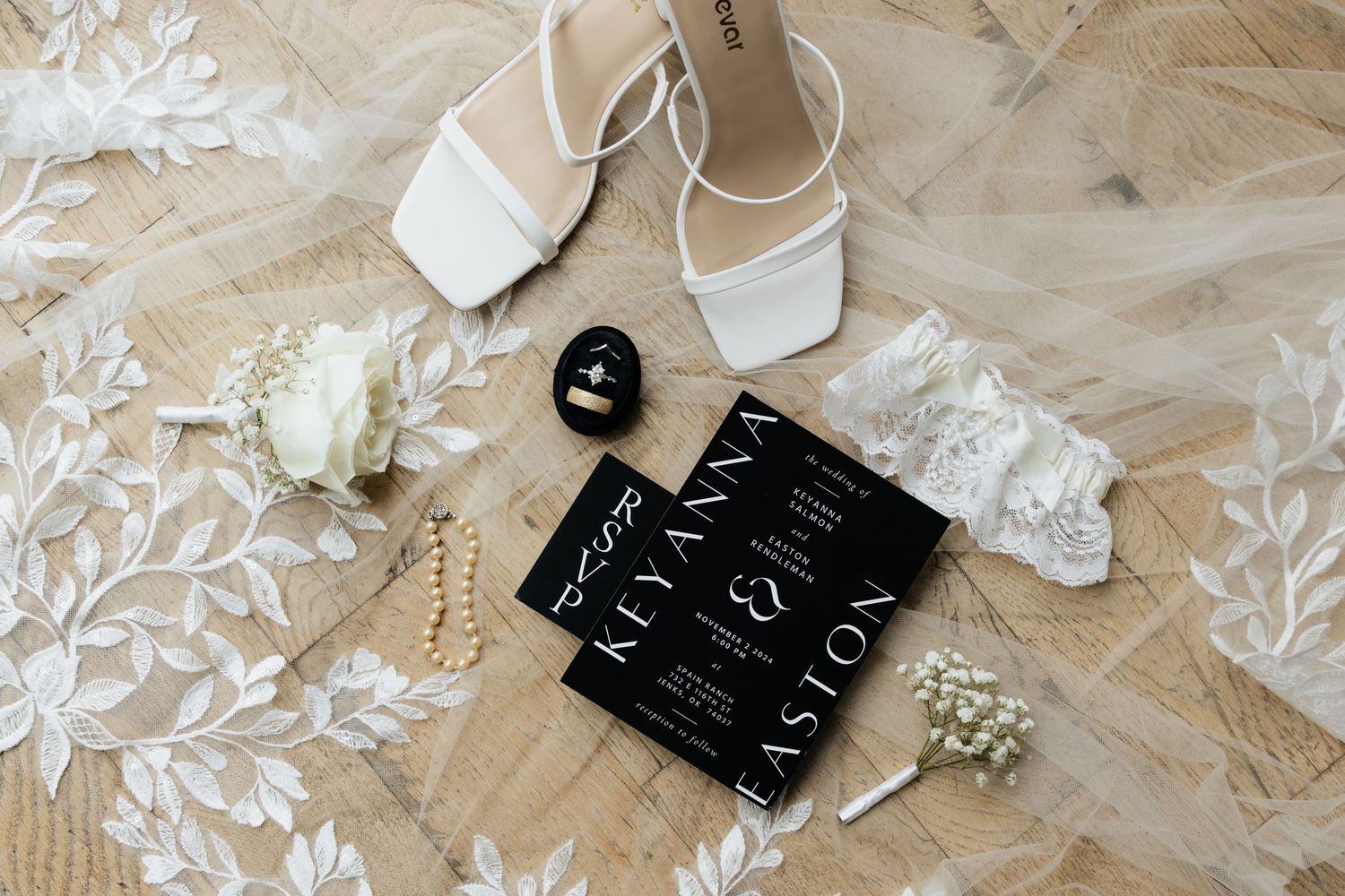 Wedding day details showing a black wedding invitation and an embroidered veil.