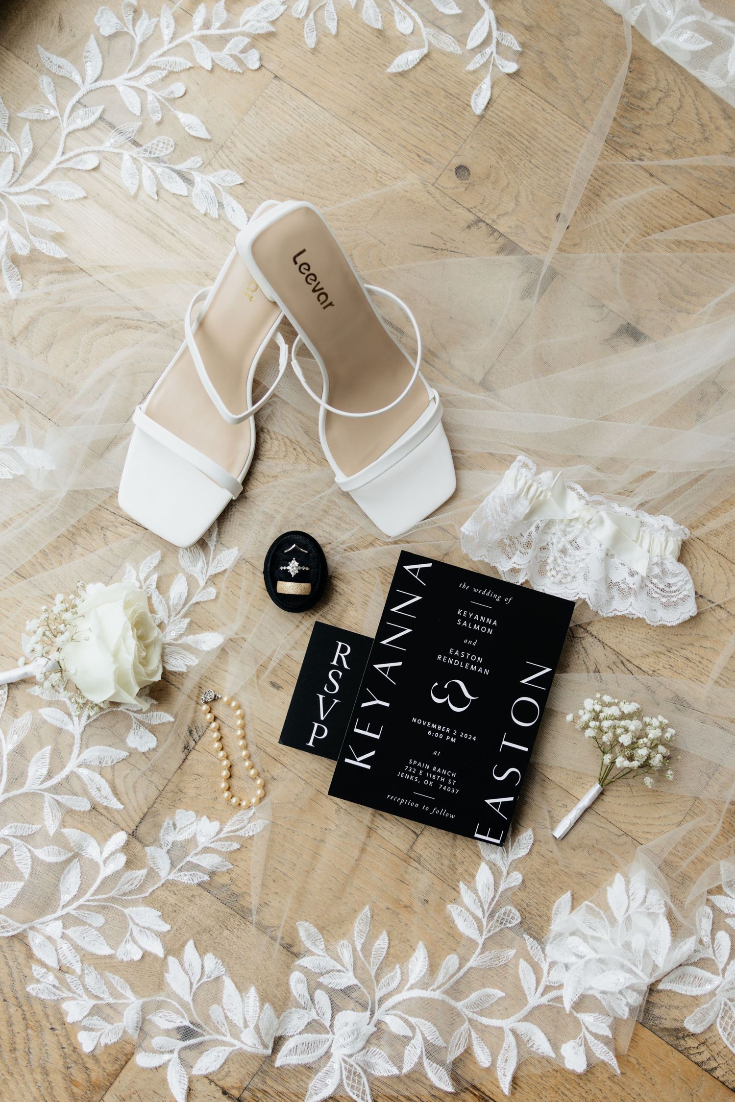 Wedding day details showing a black wedding invitation and an embroidered veil.