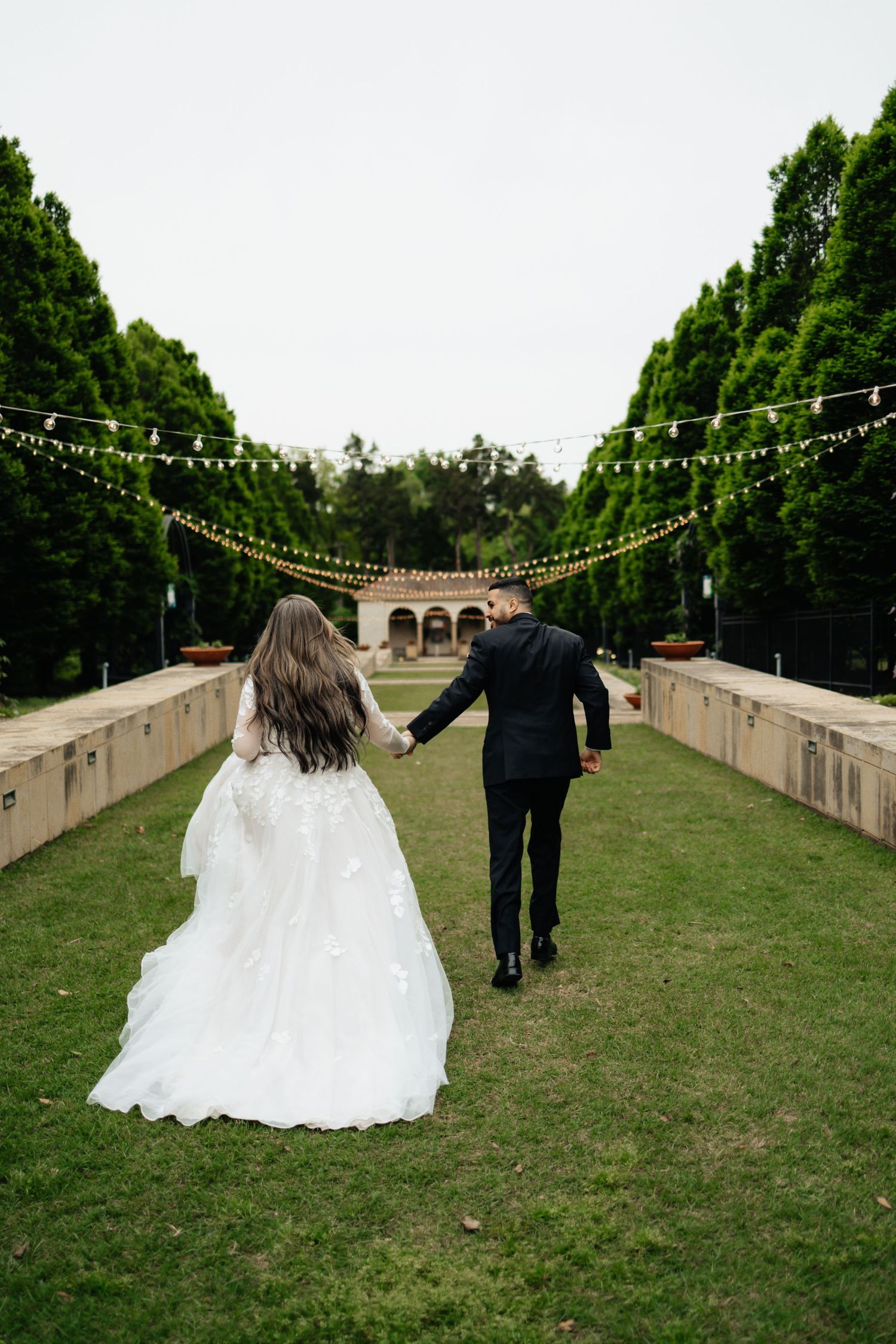 couple running. Running photos. Engagement session in the gardens. Philbrook museum of art, tulsa Oklahoma. Bride and groom. Gardens. field.