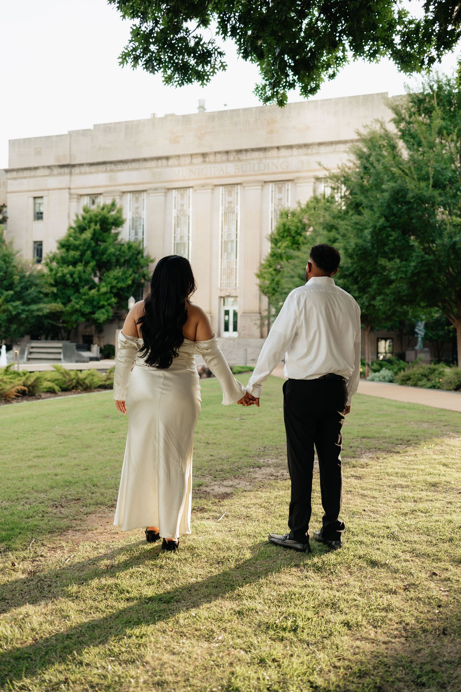 Engagement session downtown oklahoma city. Bride is wearing a white dress. Bride and groom holding hands. Intimate engagement session.