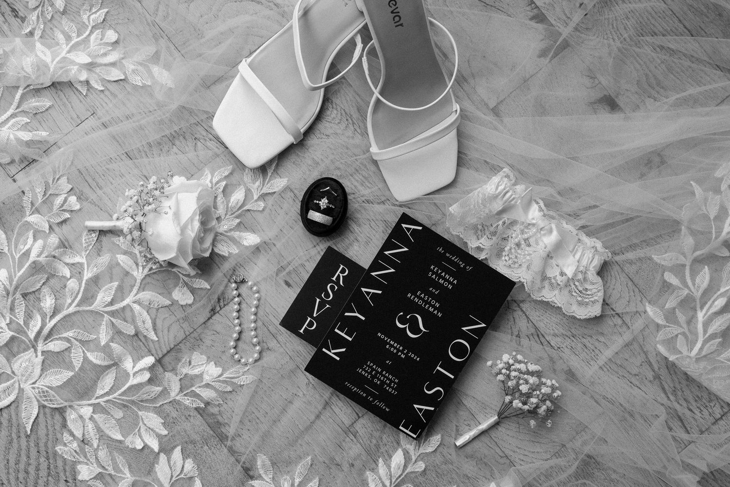 Wedding day details showing a black wedding invitation and an embroidered veil.