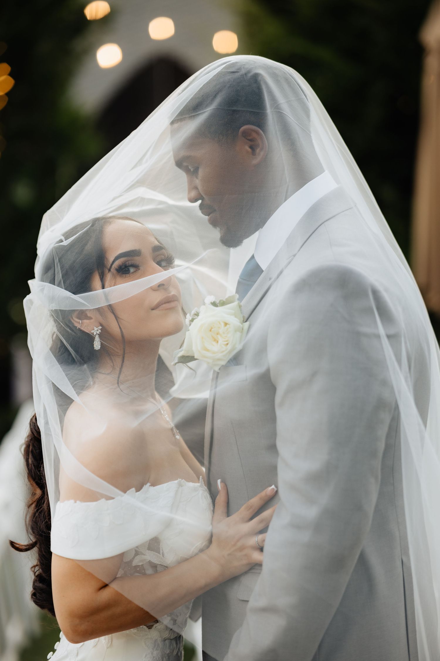 Bride and groom inside of a white wedding veil.