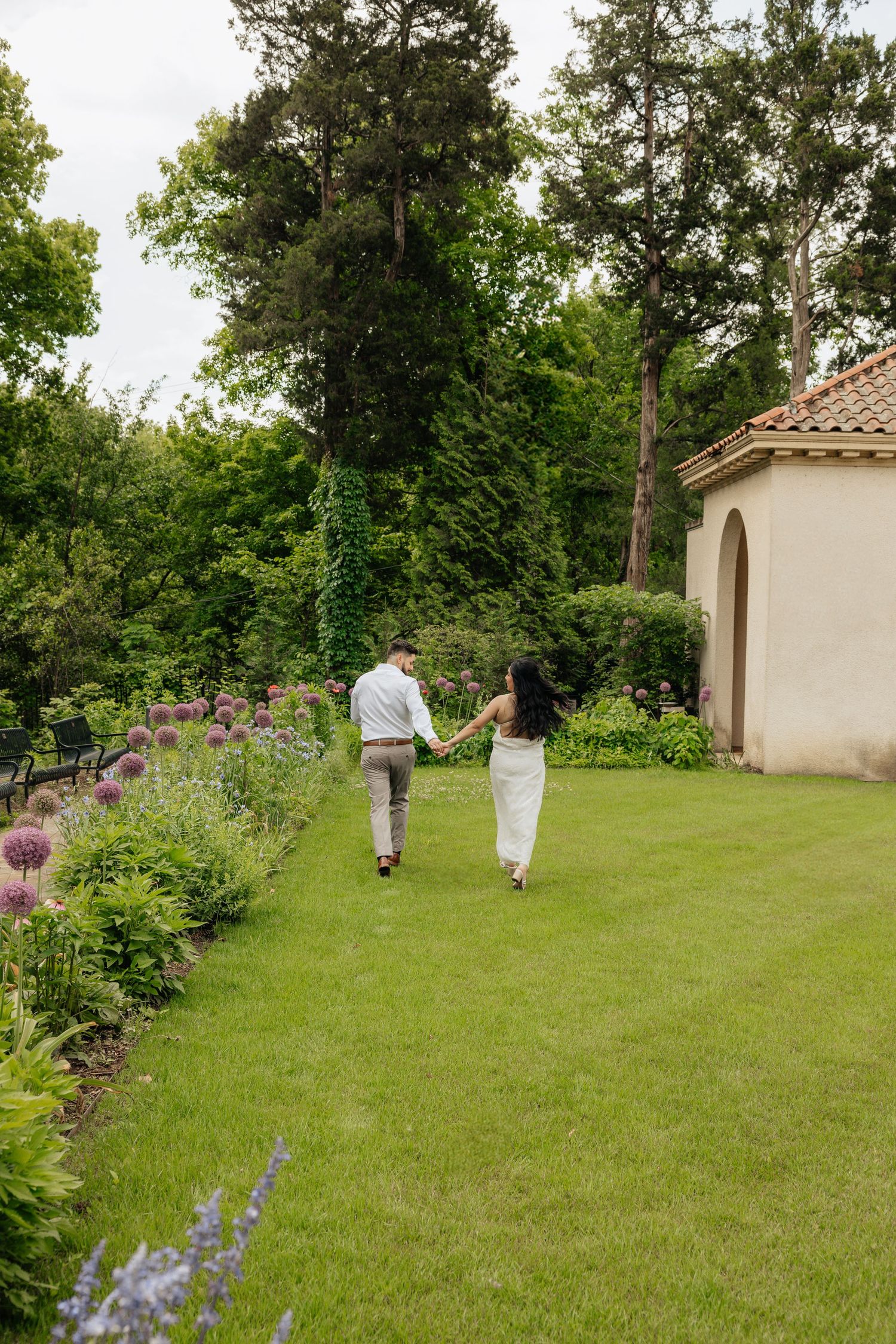 couple running. Running photos. Engagement session in the gardens. Philbrook museum of art, tulsa Oklahoma. Bride and groom. Gardens. field.