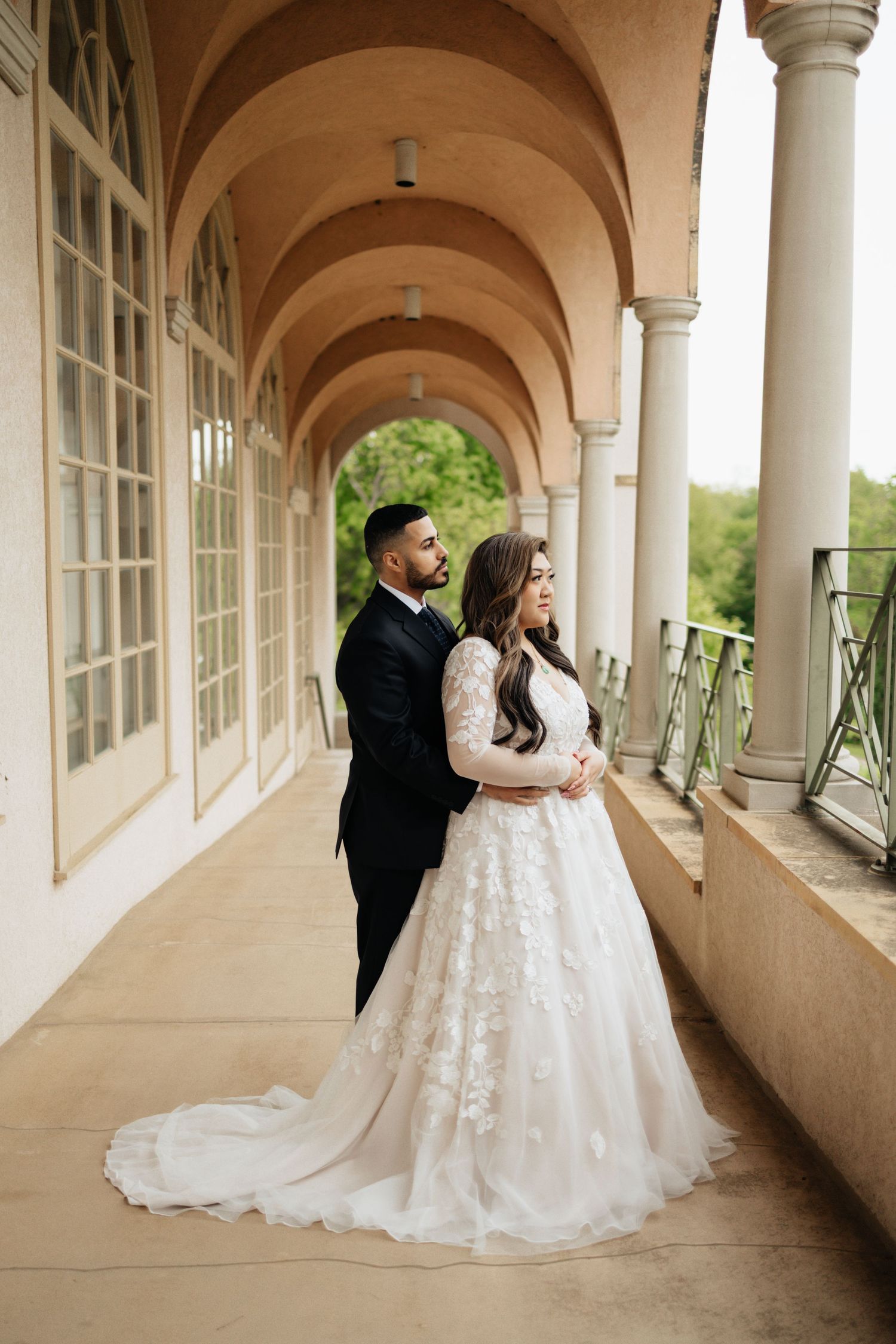 Bride and groom posing for a photo in a long hallway at the Philbrook museum of art in tulsa, oklahoma.