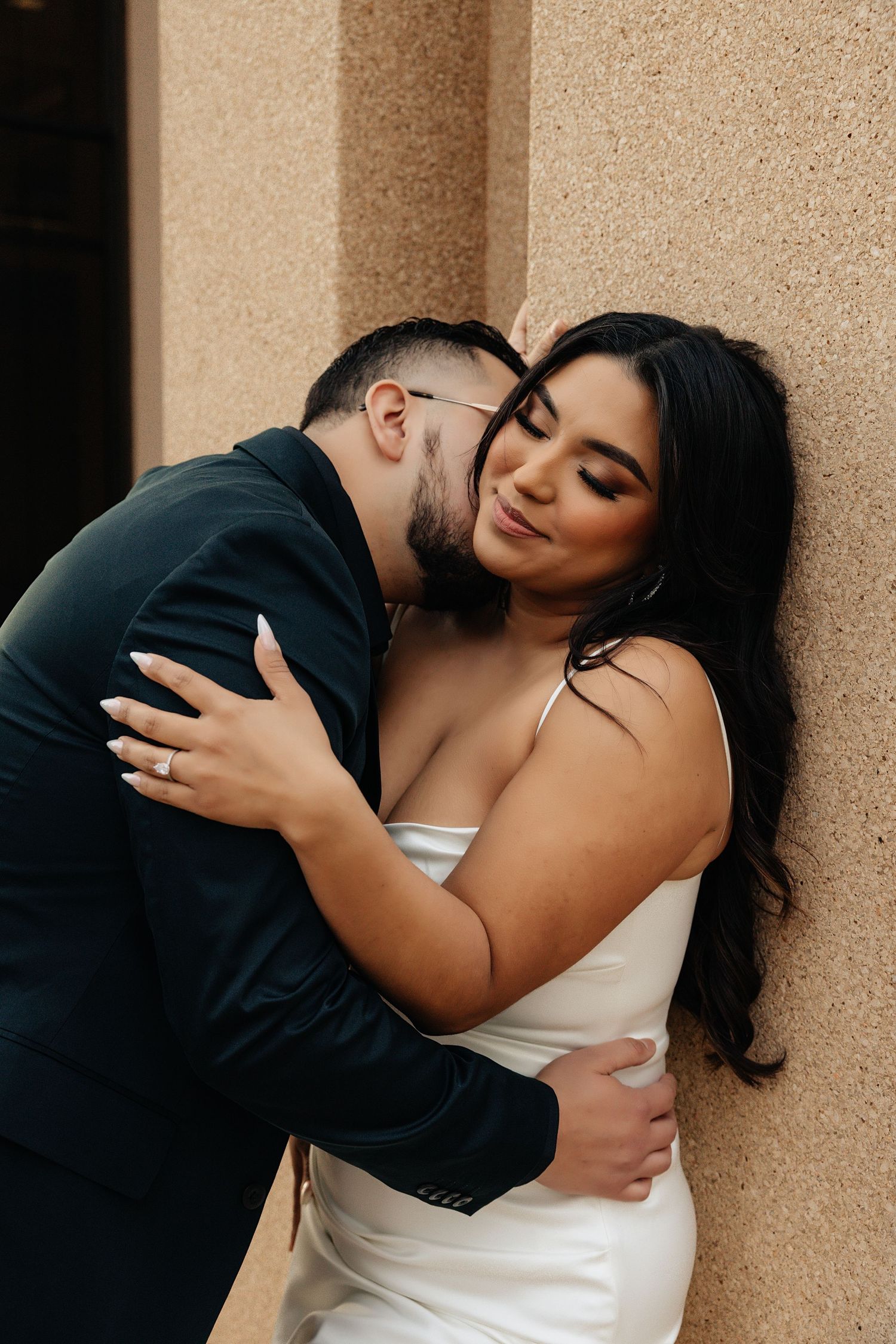 Engagement session downtown oklahoma city. Bride is wearing a white dress while groom is kissing her. Intimate engagement session.