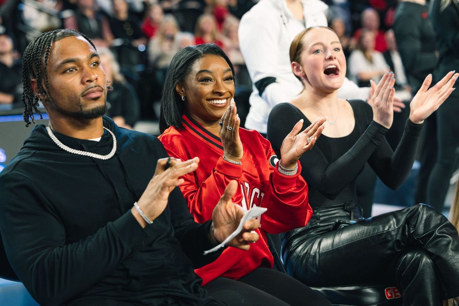 Spectators cheering enthusiastically from their seats at an indoor sporting event.