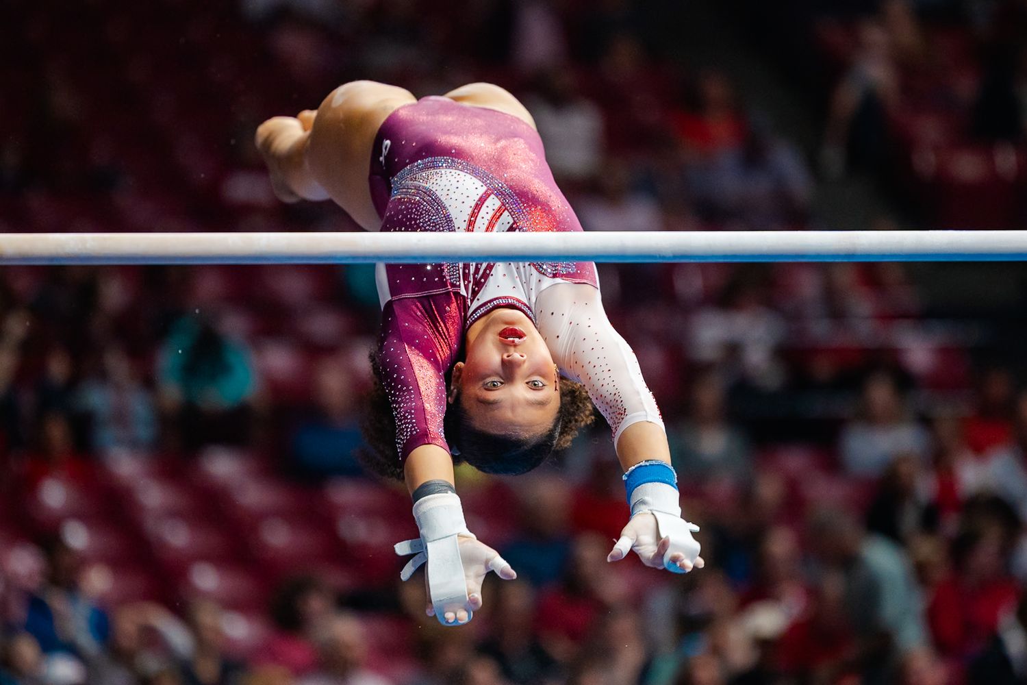 Gymnast performs a graceful rotation on the horizontal bar during a competitive routine.