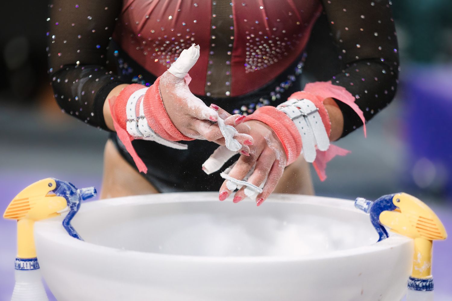 Close up of hands applying chalk over a gymnastics bowl.