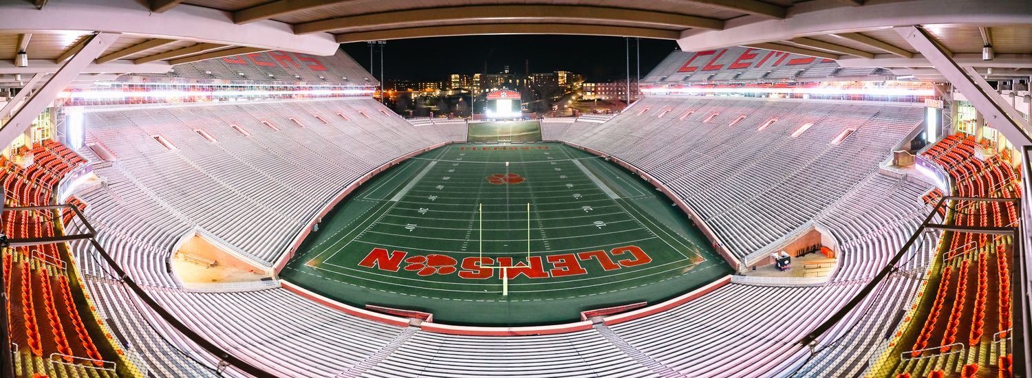 Aerial view of large football stadium with orange seats and green field.