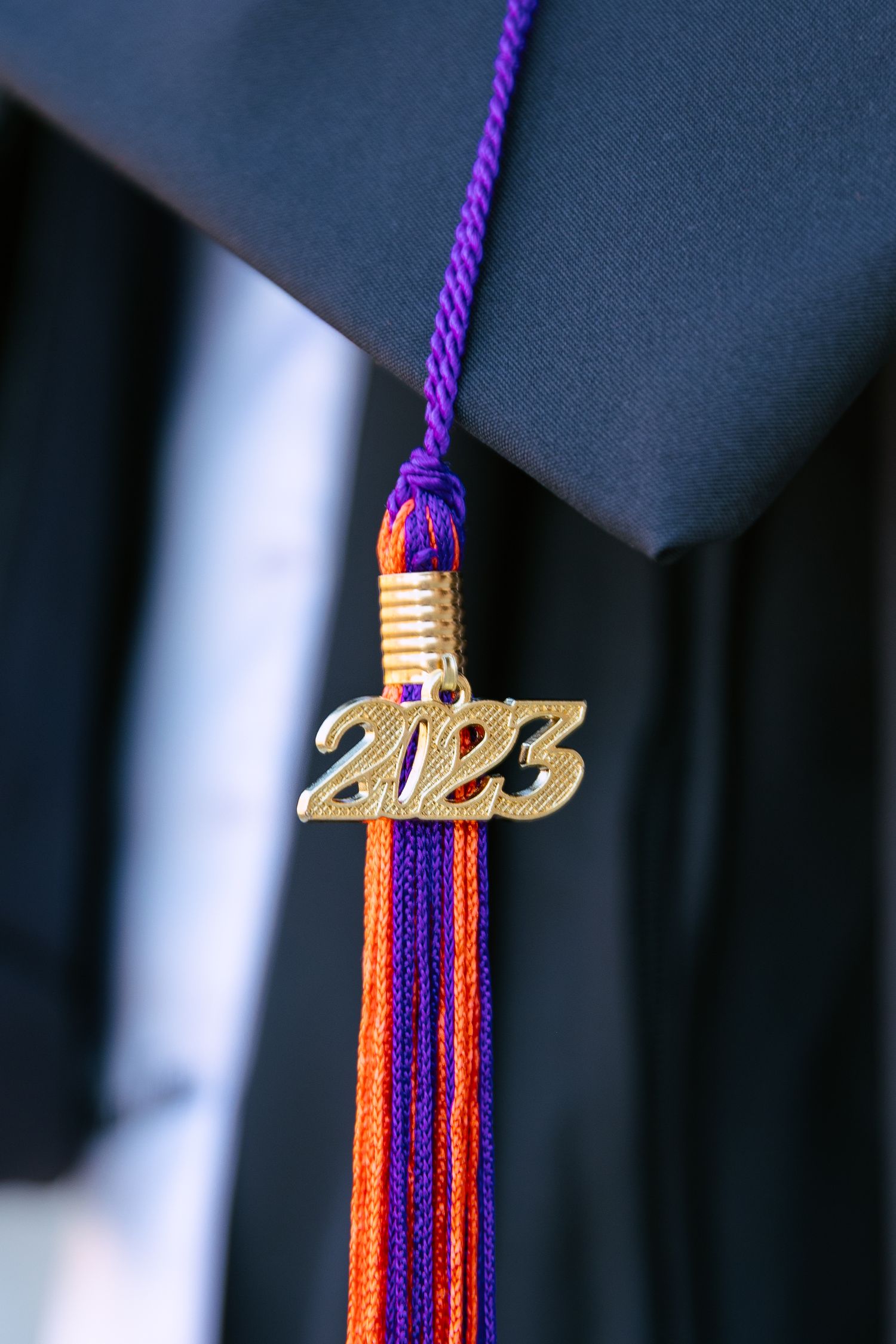Graduation tassel with gold 2023 charm in purple and orange school colors.