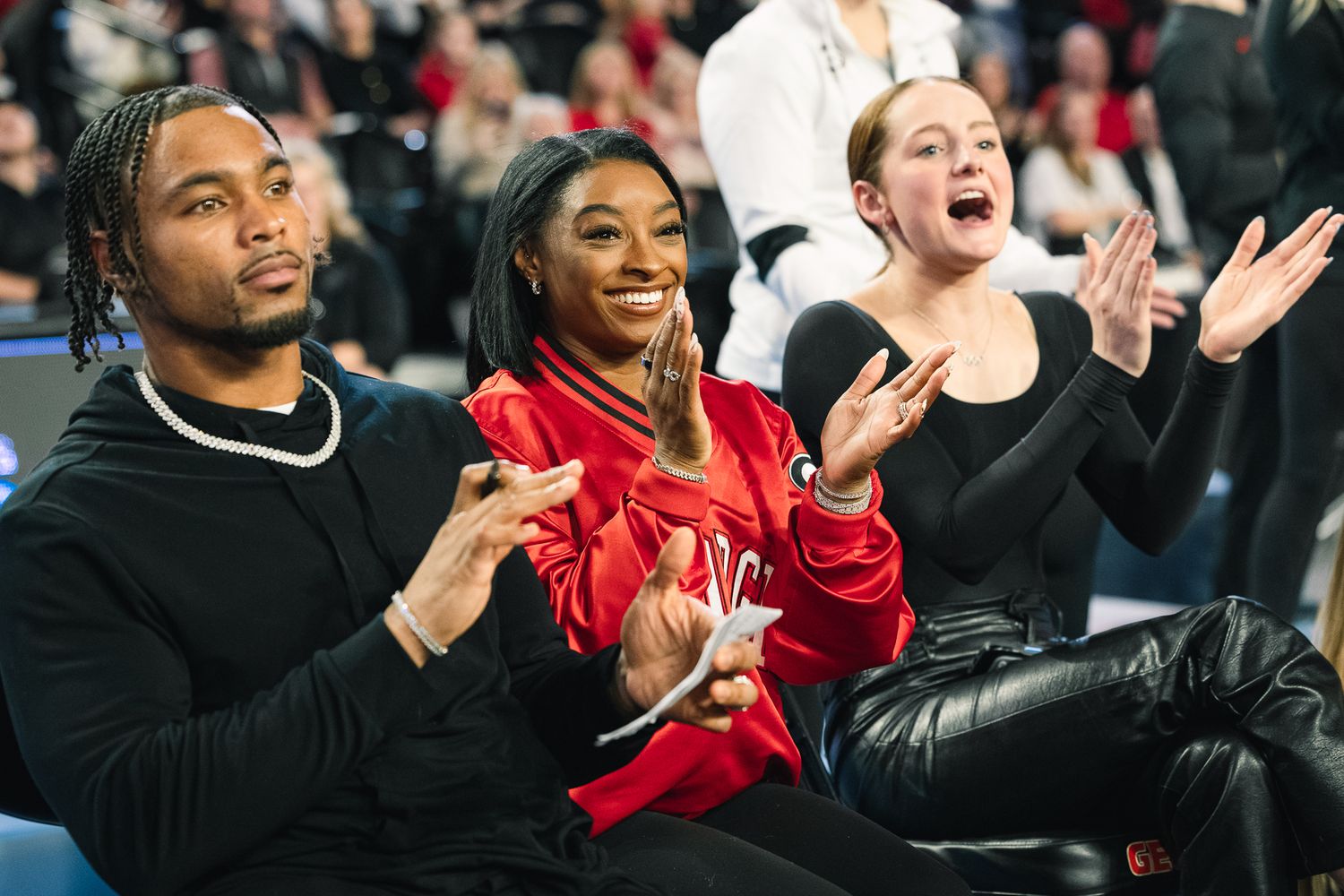 Basketball fans cheer and celebrate from their courtside seats during an exciting game moment.