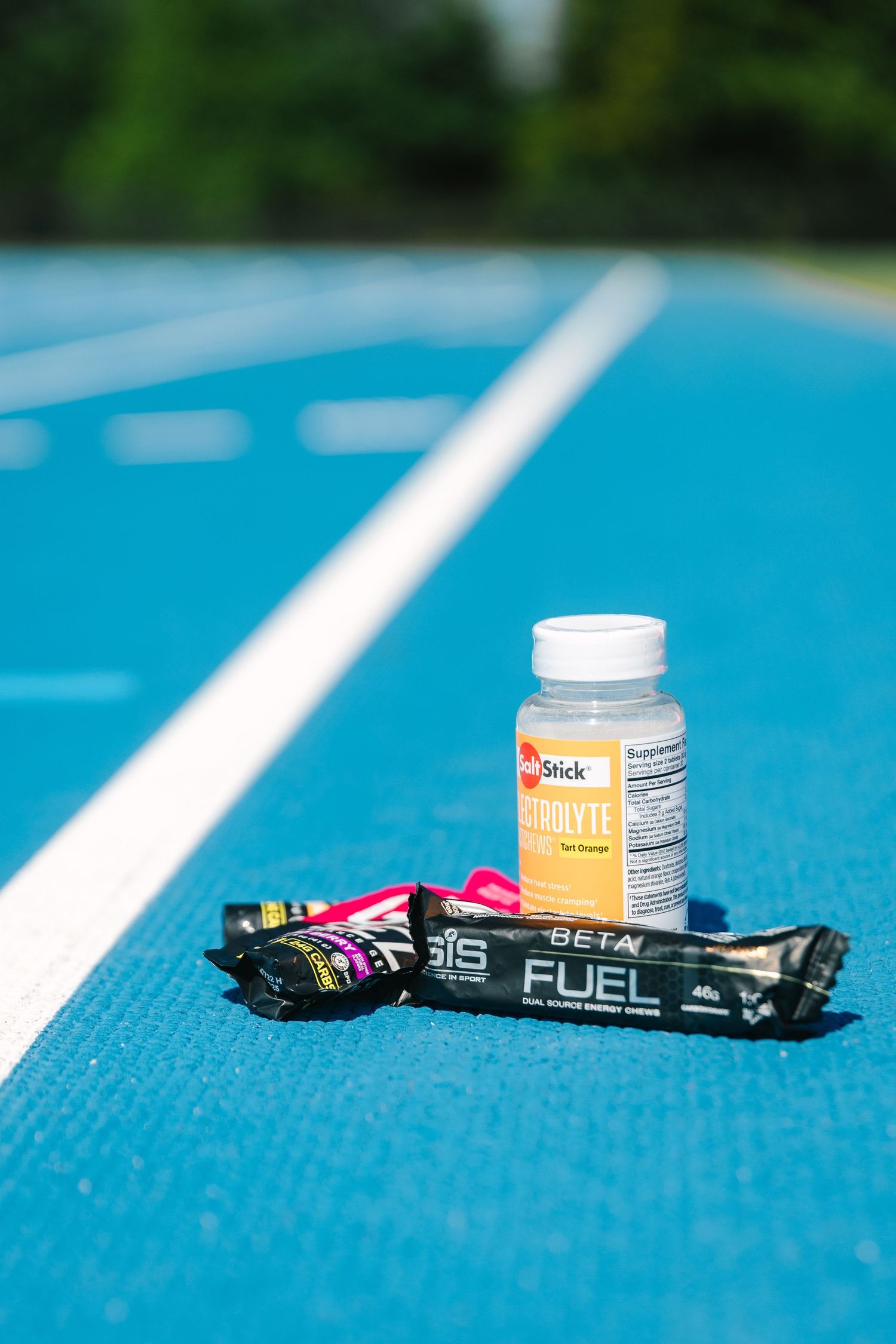 Fitness supplements and energy gel packets arranged in a row on a bright blue textured surface.