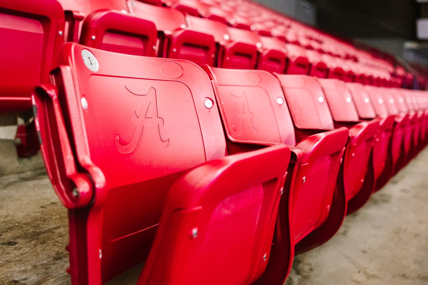Red stadium seats line up in rows creating a repeating pattern in a sports venue.