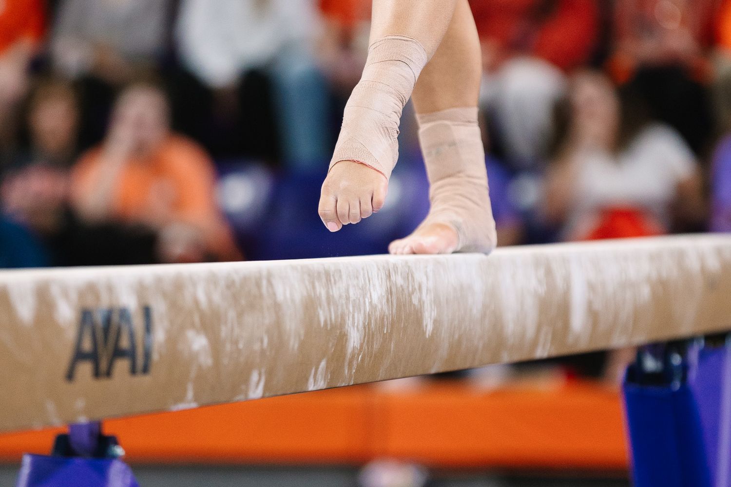 Close-up of gymnast's feet and bandages on balance beam during competition.