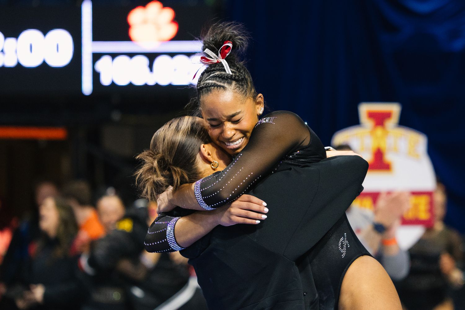 A joyful celebration with teammates hugging at a gymnastics competition.
