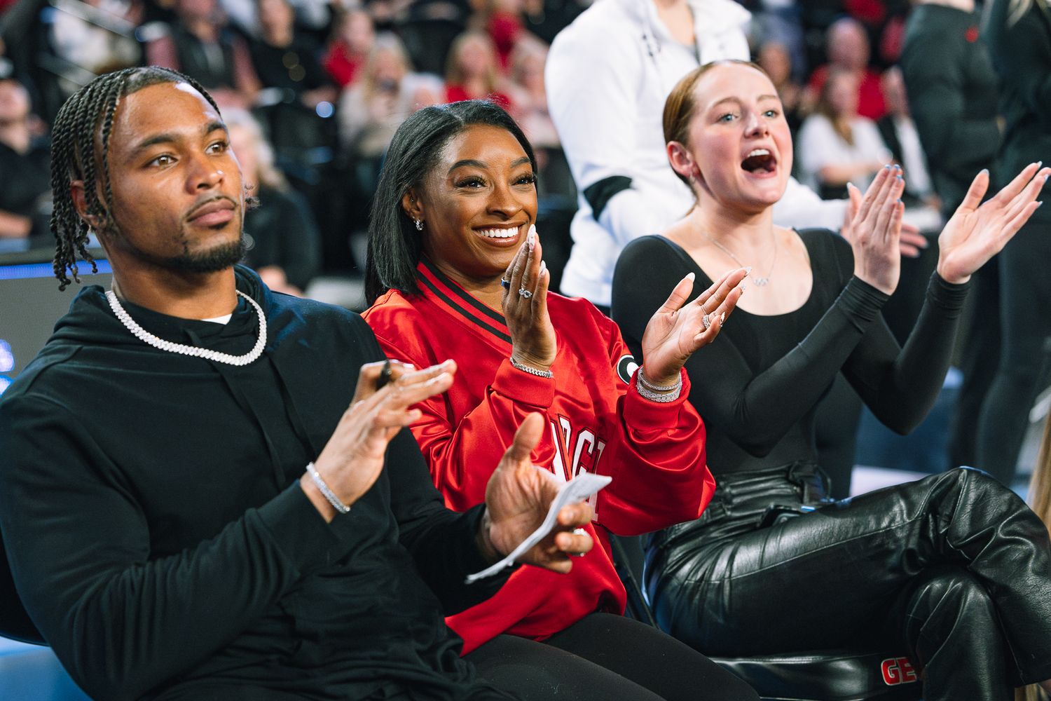 Three spectators show excitement while sitting courtside at a sports event.