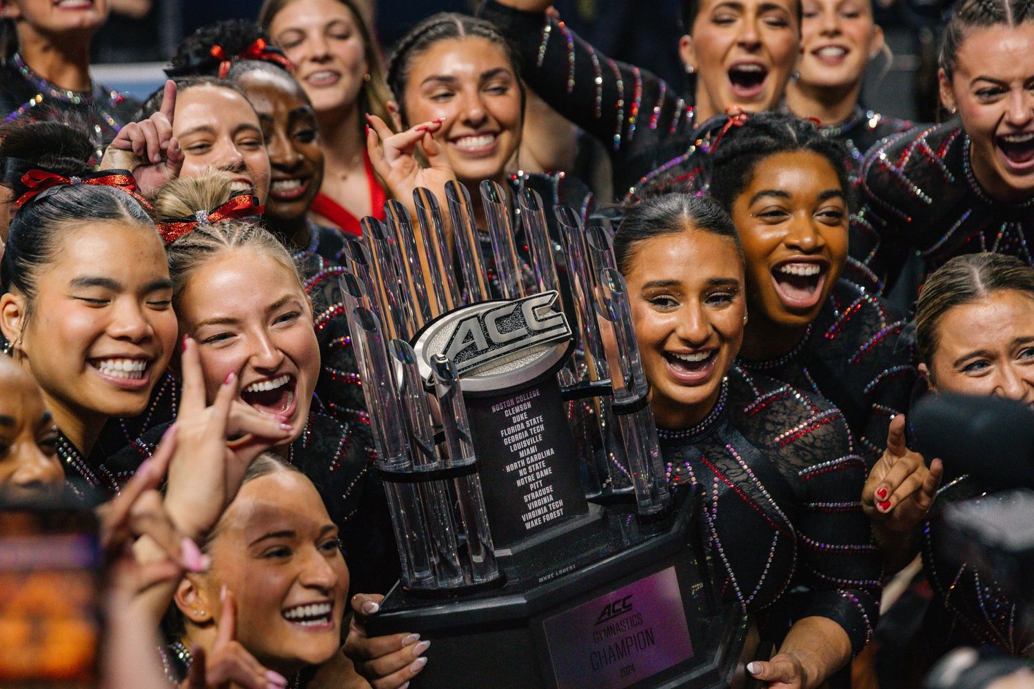 Team celebrates with championship trophy after winning competitive event.