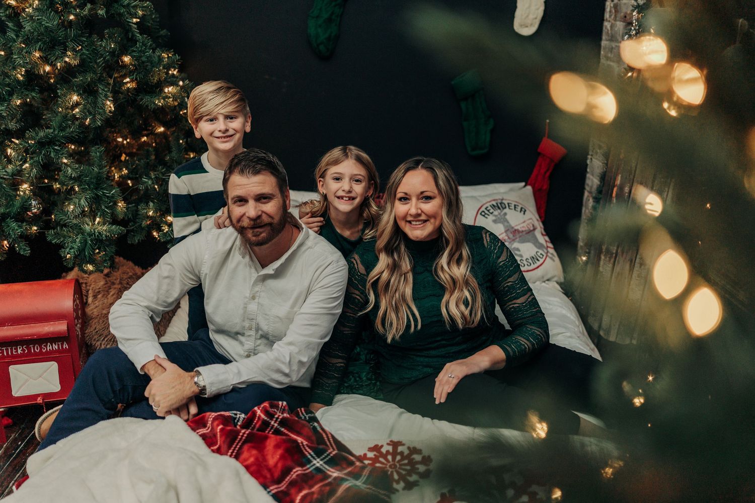 A cozy family Christmas scene with a decorated tree and soft bokeh lights in the background.