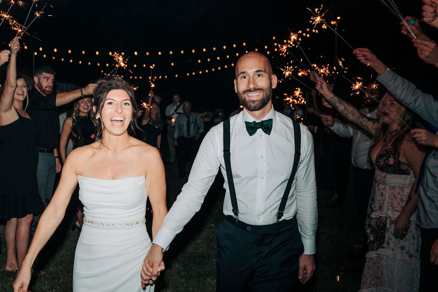 Wedding reception dance party under twinkling string lights at night.