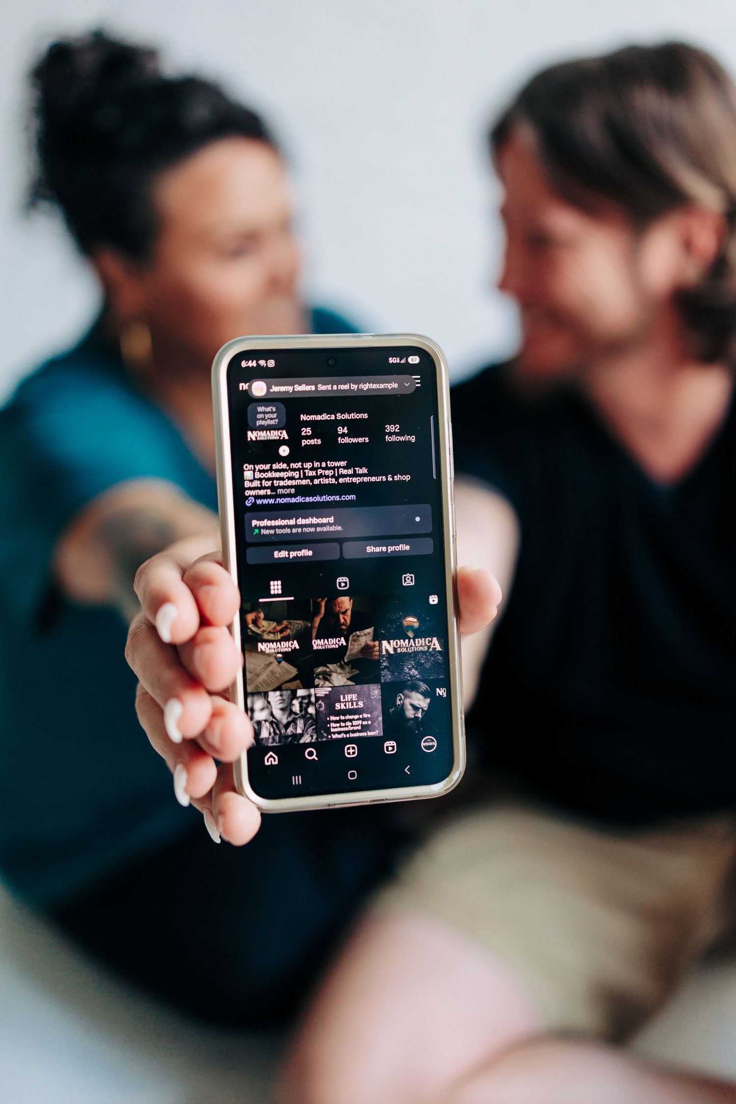 Hand holding smartphone displaying dark mode social media interface.