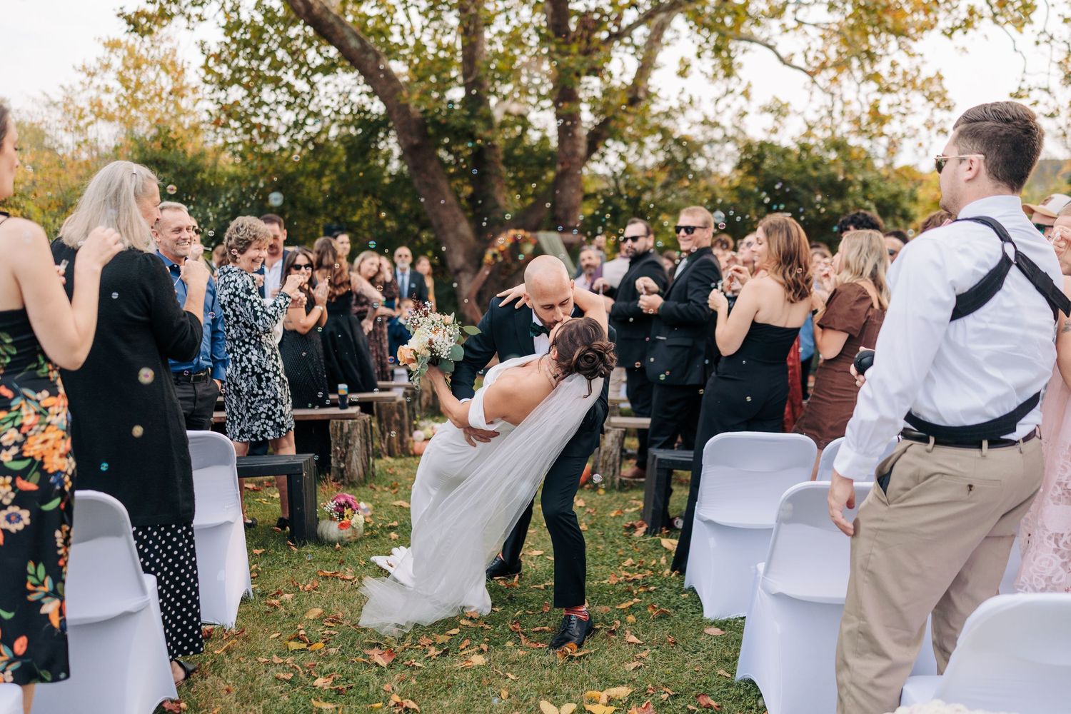 Wedding ceremony guests react emotionally during an outdoor autumn celebration.