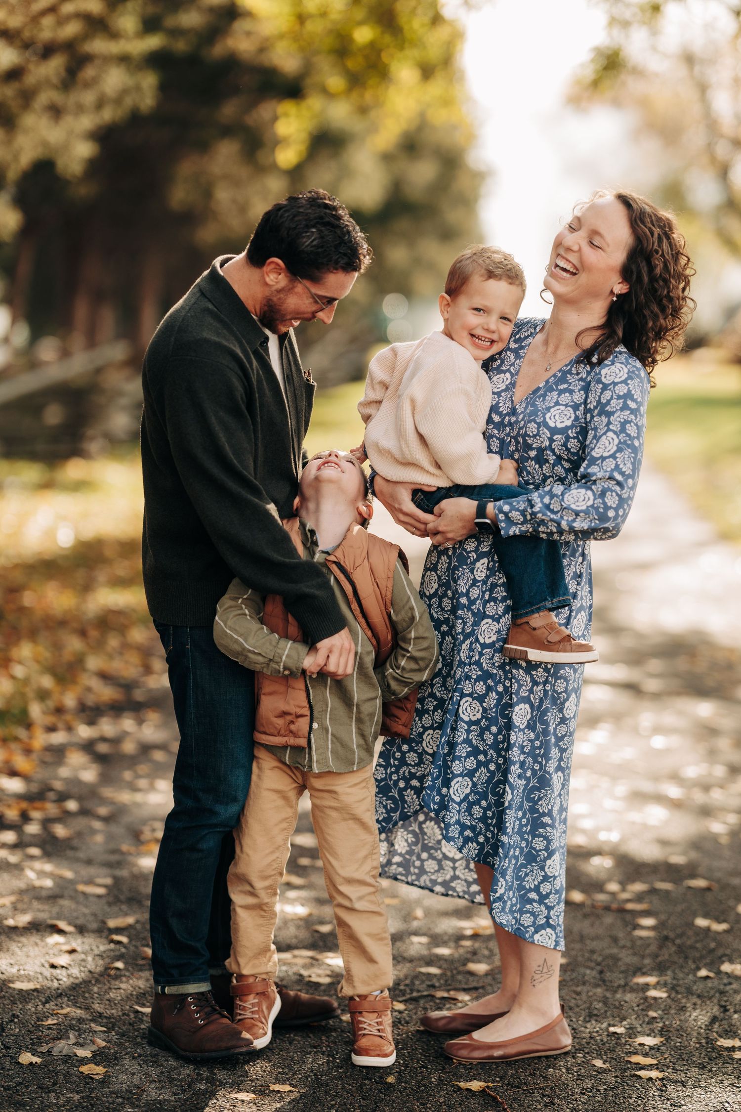 A joyful family shares a tender moment together on a sunlit autumn path in a park.